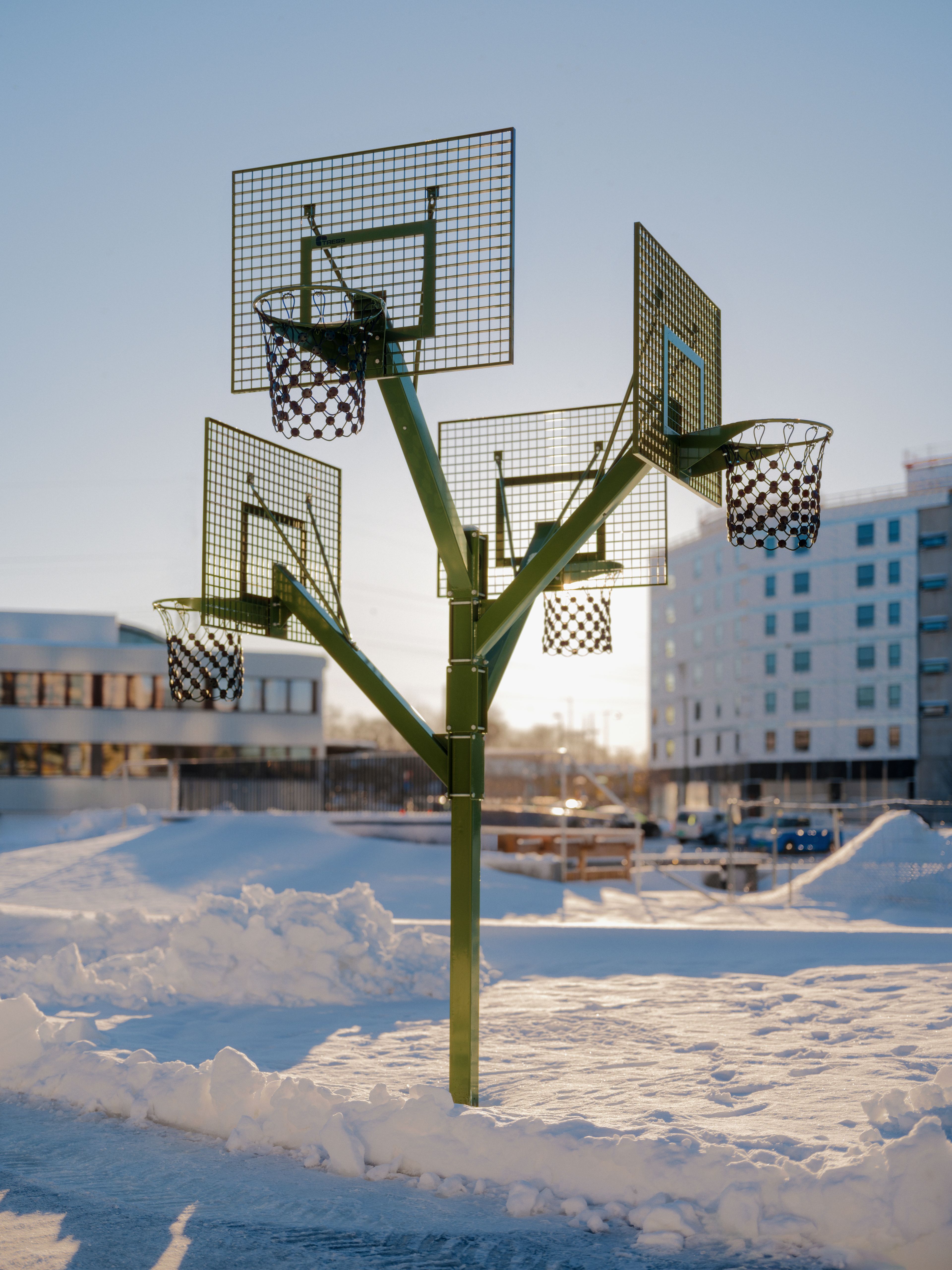 Fire basketballkurver på et grønt stativ med et snødekt Ulven i bakgrunnen