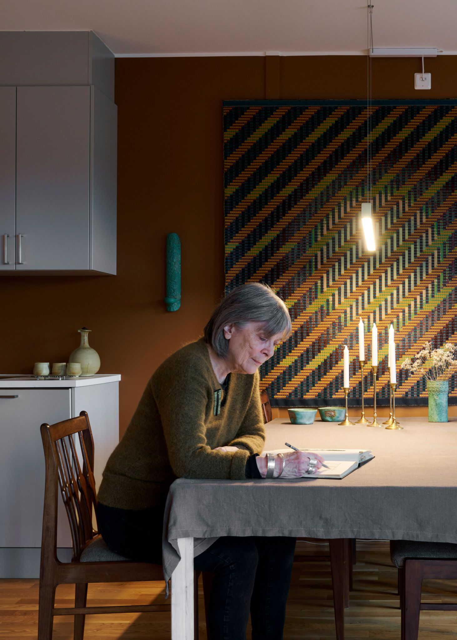 Foto av Marit ved spisebordet sitt i den nye leiligheten i Sandsliåsen.