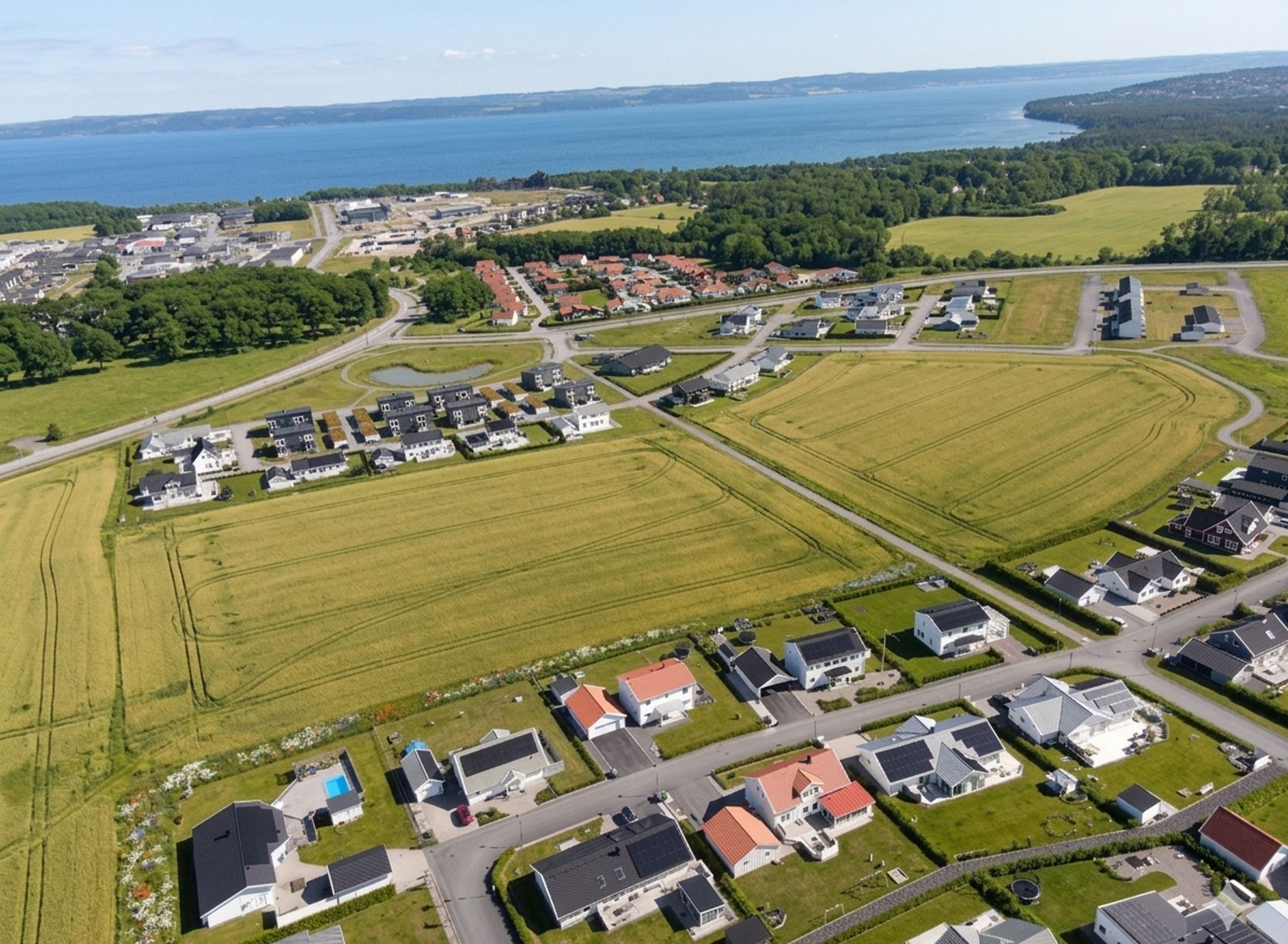 Flygfoto över området där Solhöjden ska ligga. Villakvarter och Vättern i bakgrunden.