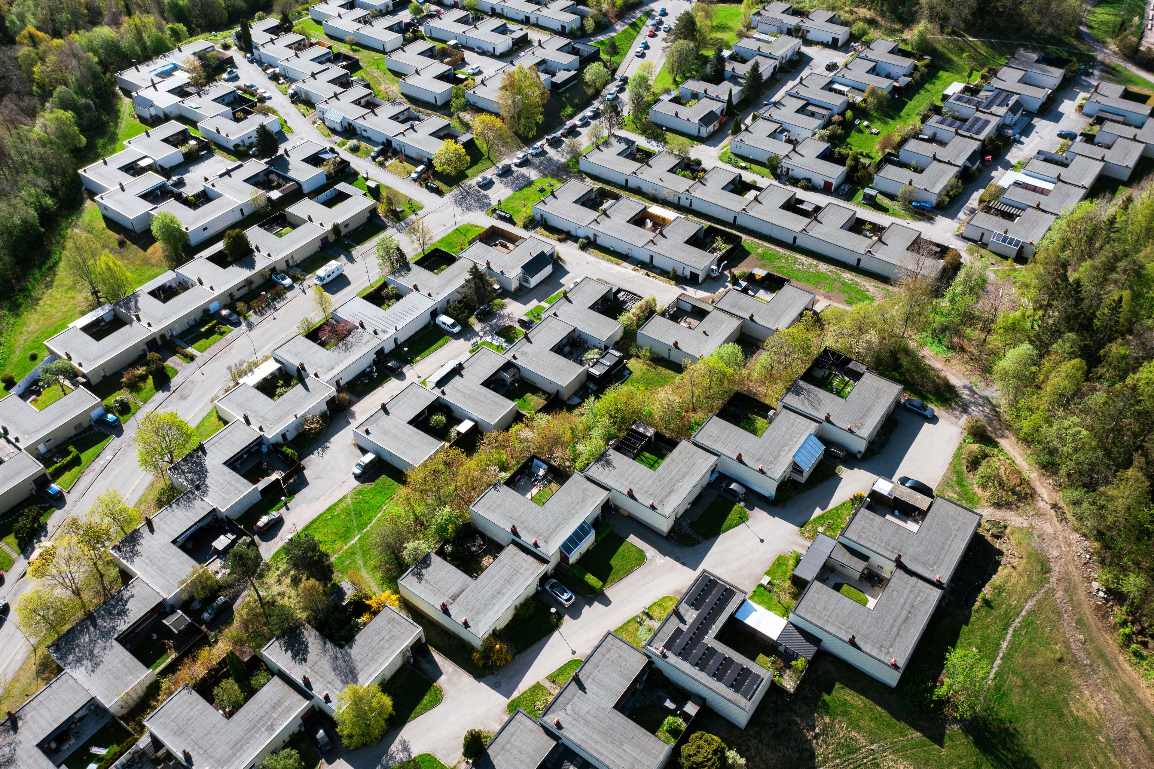 Dronefoto av et tettbygd rekkehusområde omgitt av trær og grønne fellesarealer
