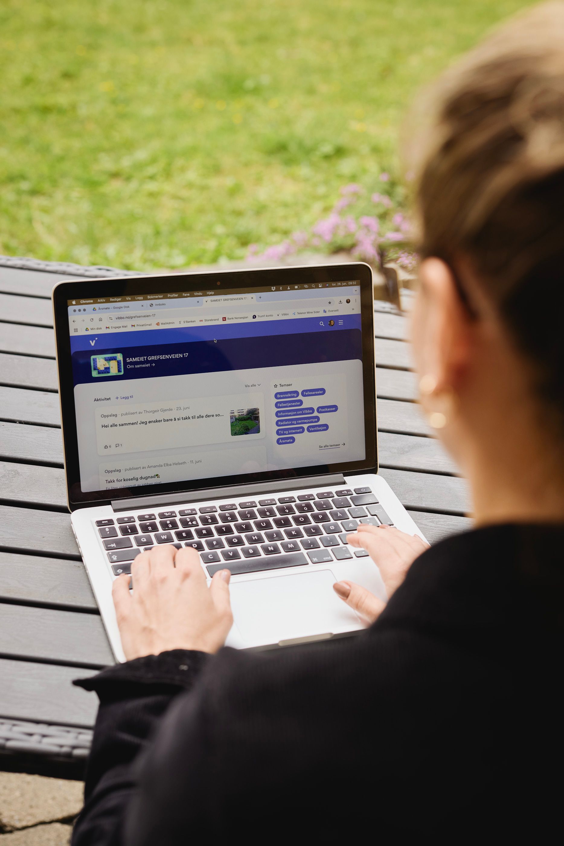 Kvinne sitter ved en benk utendørs og ser på sin laptop