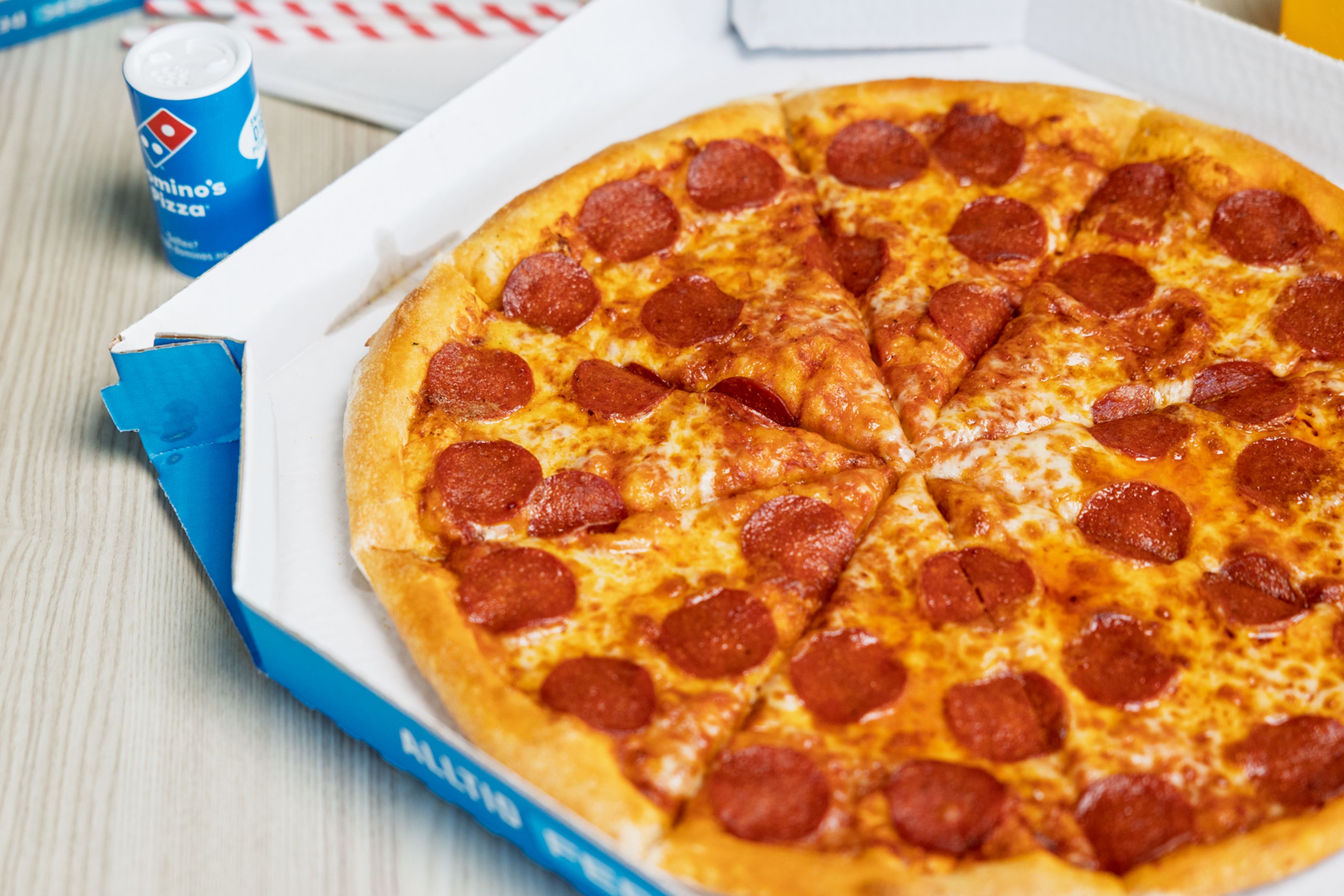 På bildet ser du flere pizzaer rundt et bord. Det er forskjellig tilbehør, som eksempelvis Pepperoni.