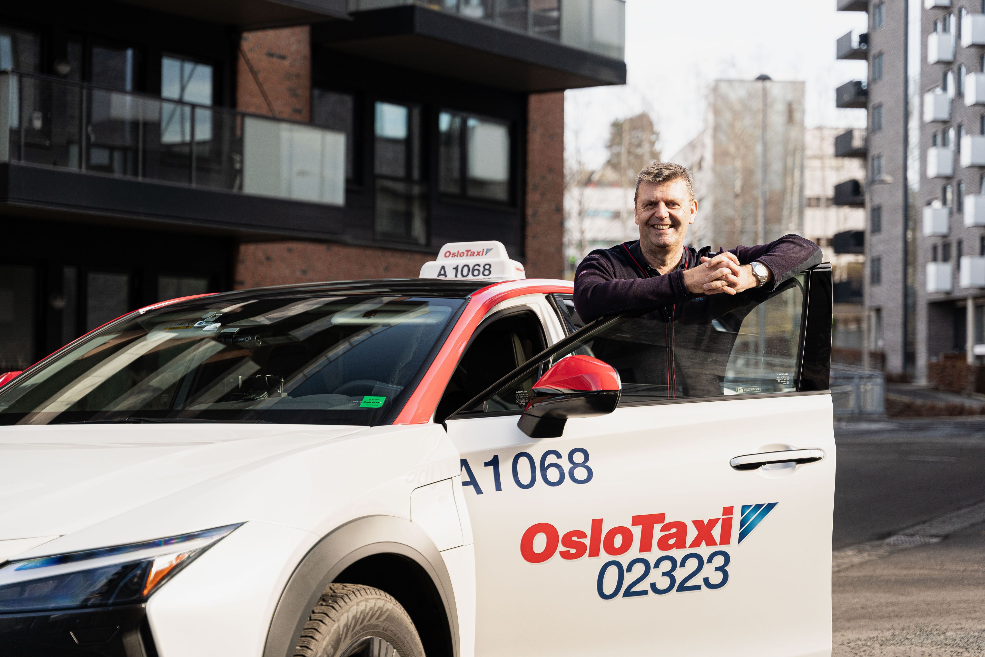 Taxisjåfør som står ved siden av en Oslo Taxi-bil.