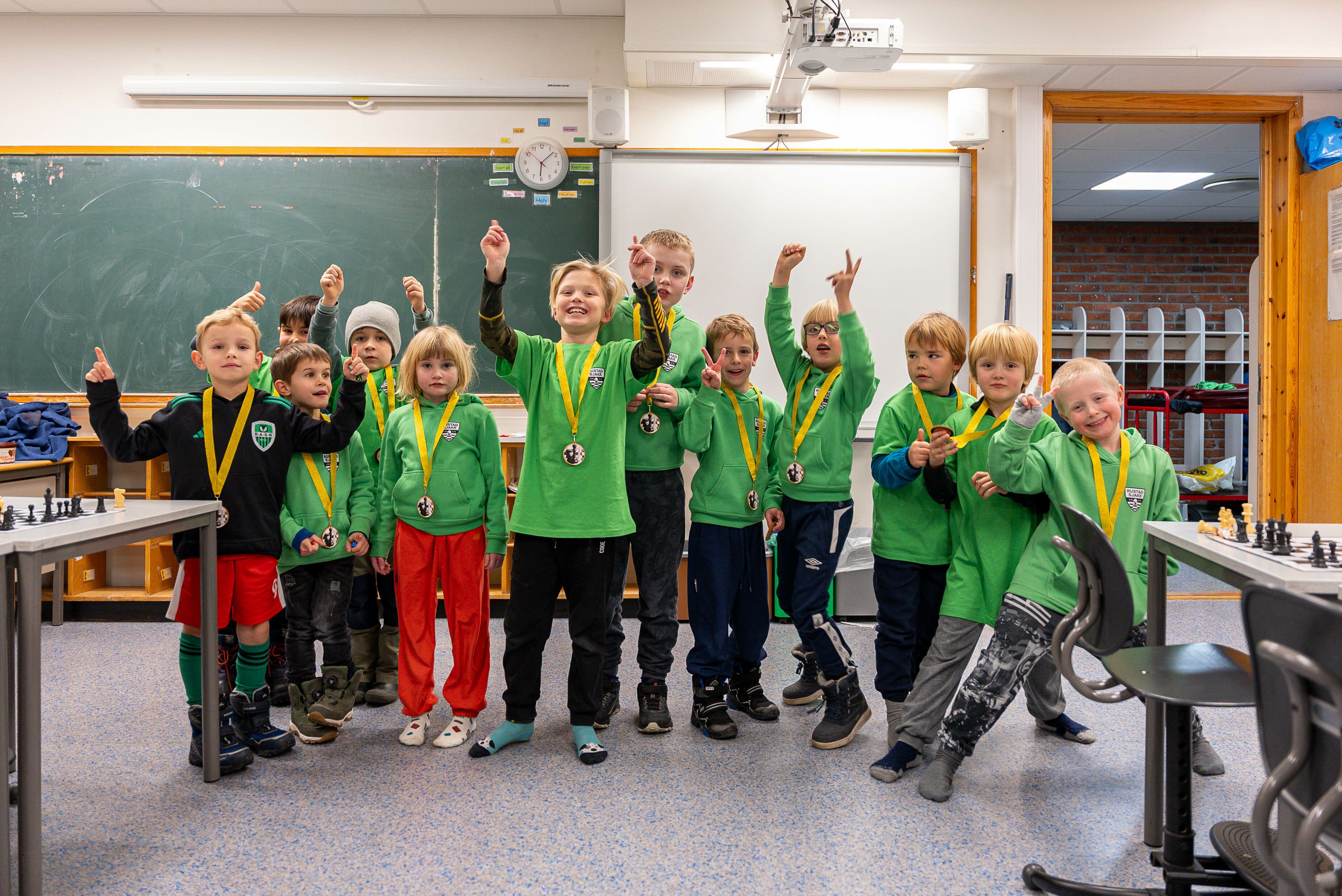 Mange barn som står og jubler i et klasserom.