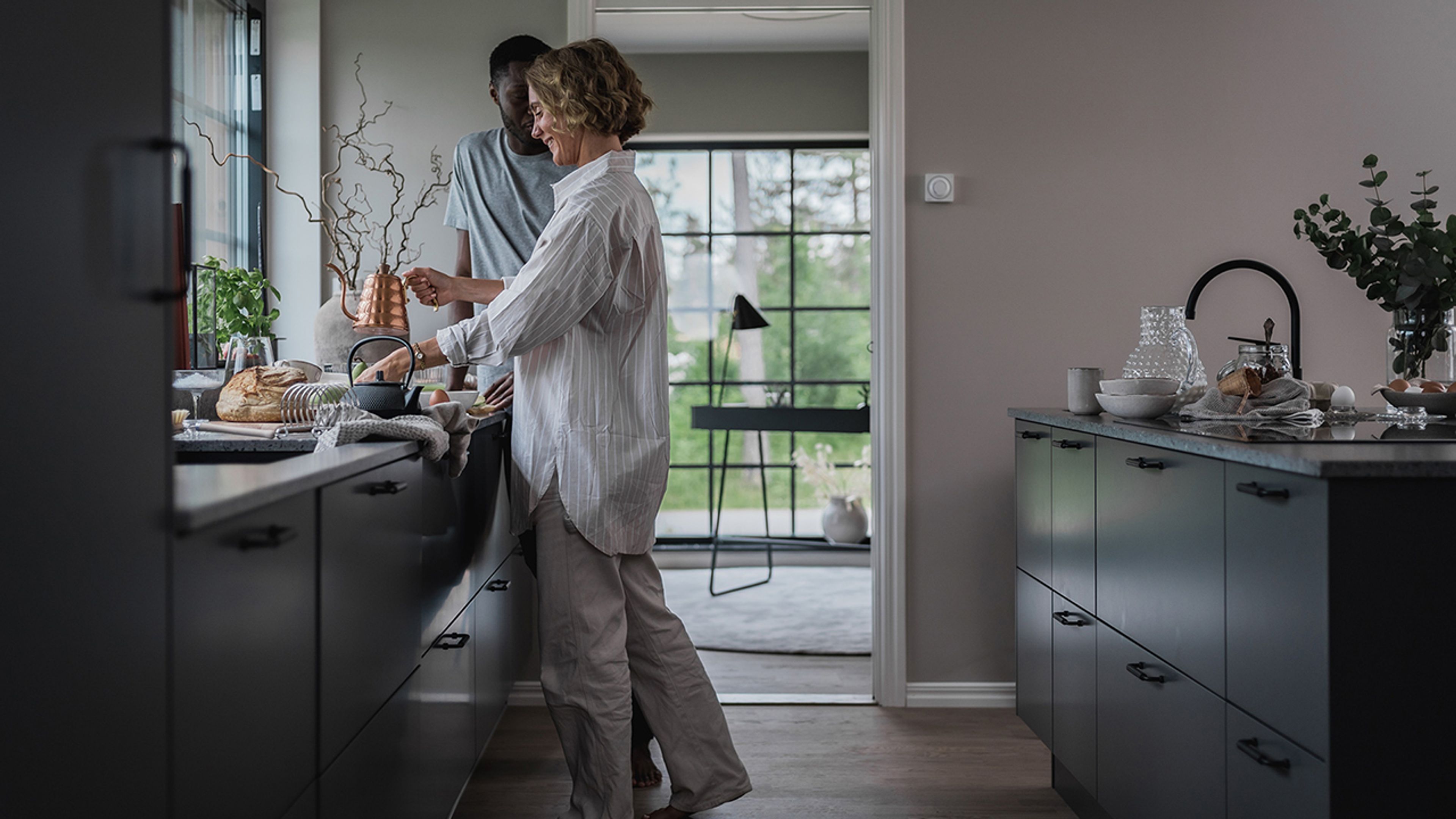 Mann og kvinne står på kjøkkenet og lager mat sammen.