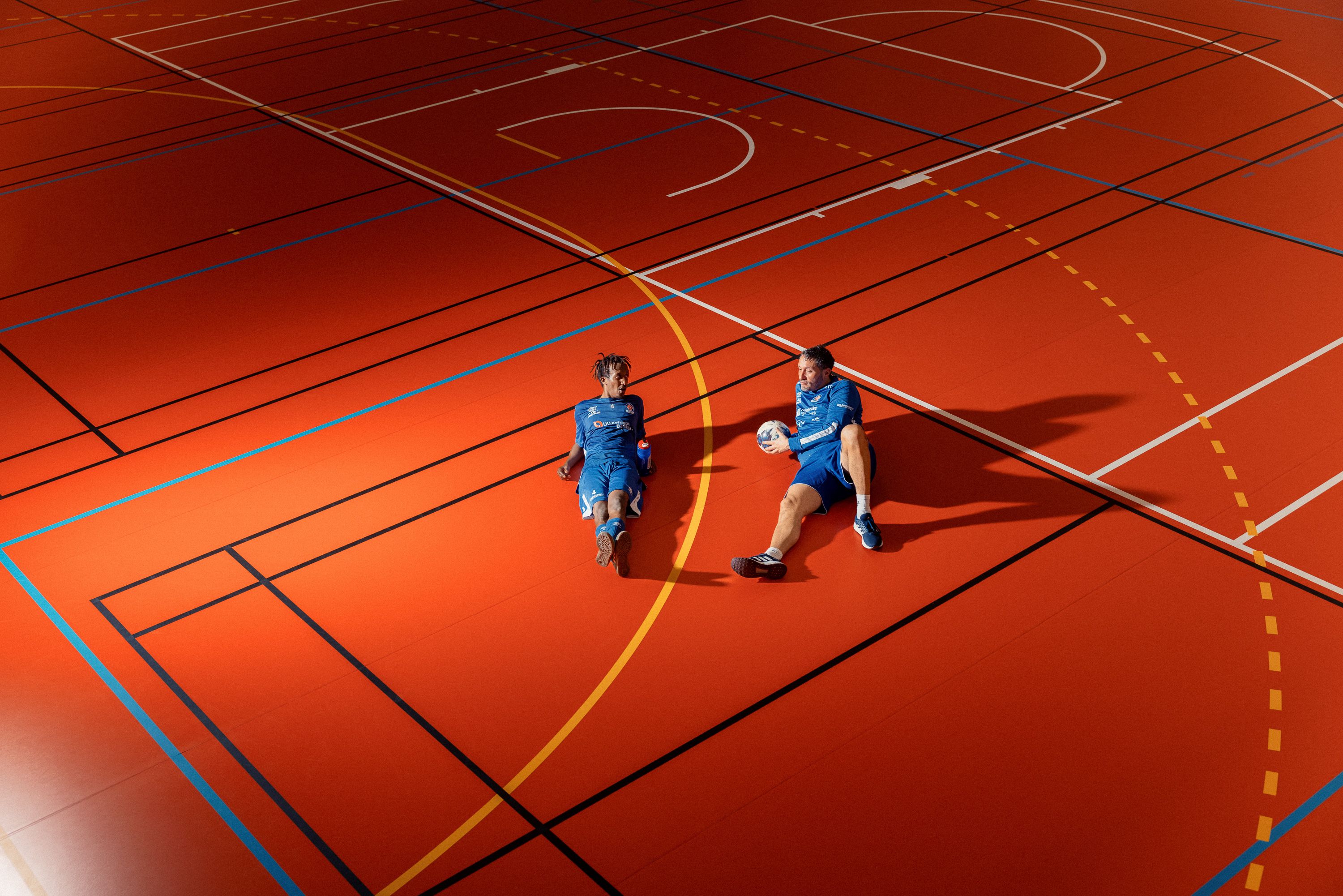 To gutter har lagt seg ned på gulvet i en idrettshall.