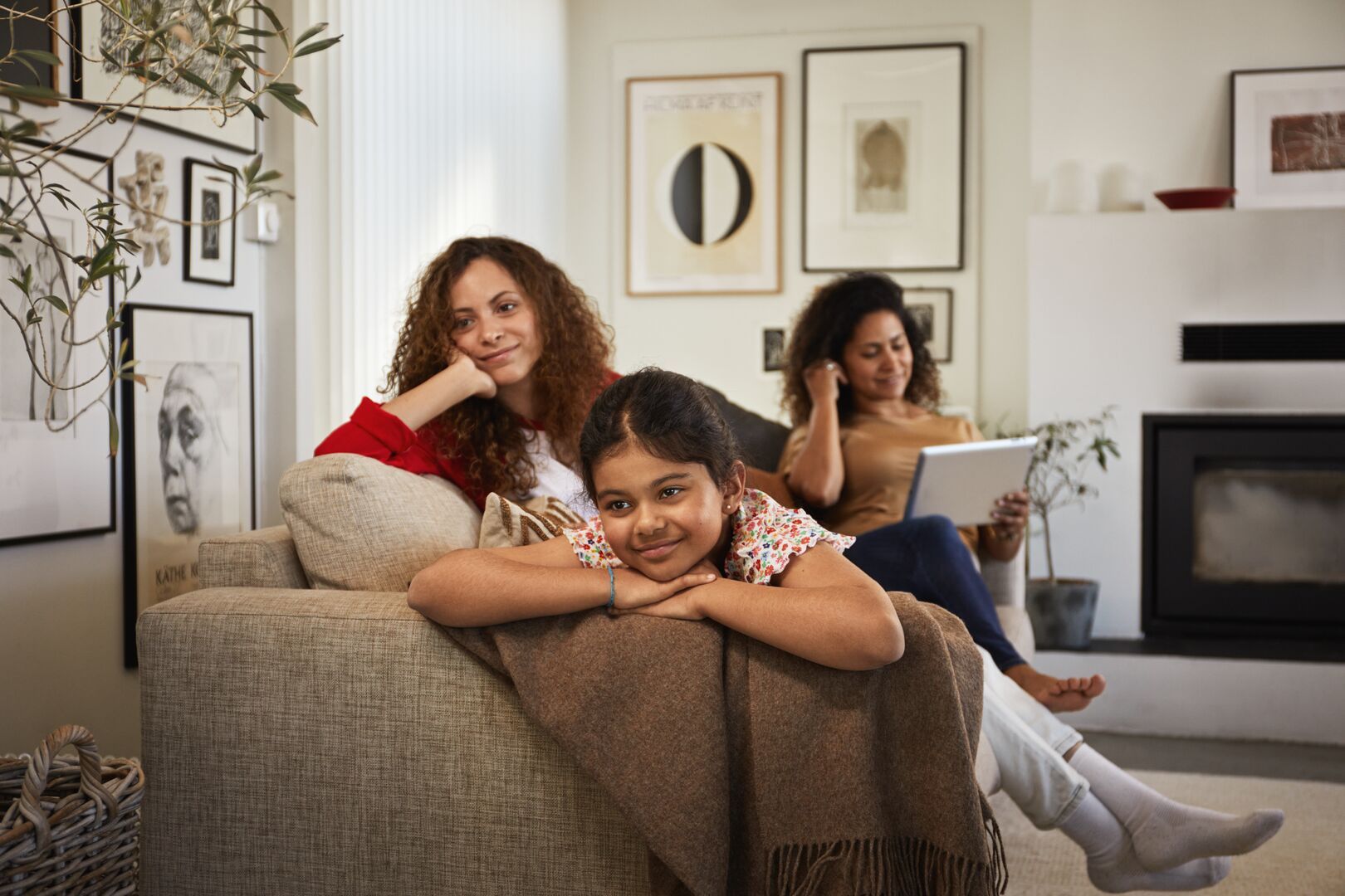 Tre personer ser på TV i sofaen.