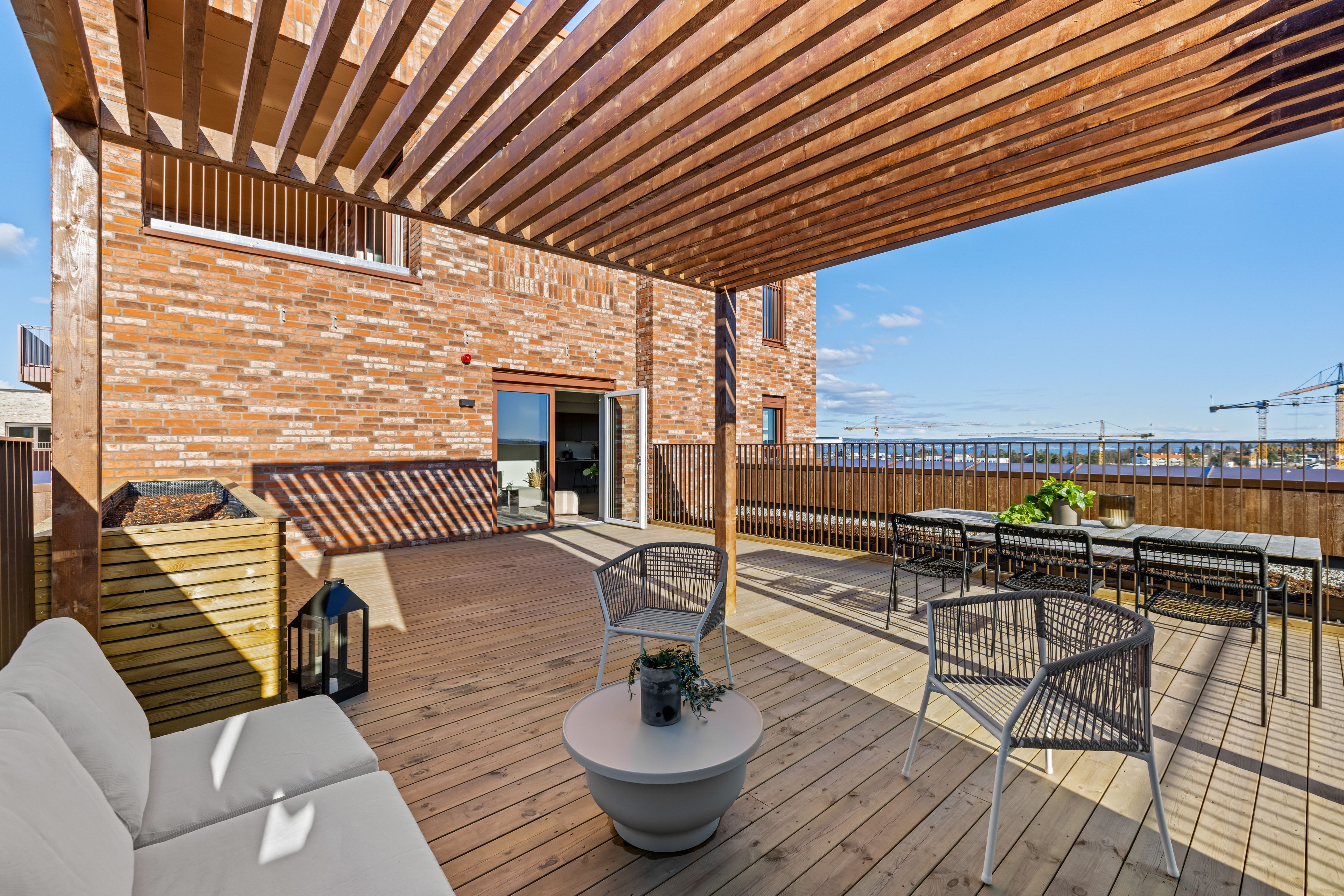 Privat takterrasse med pergola og spiseplass.