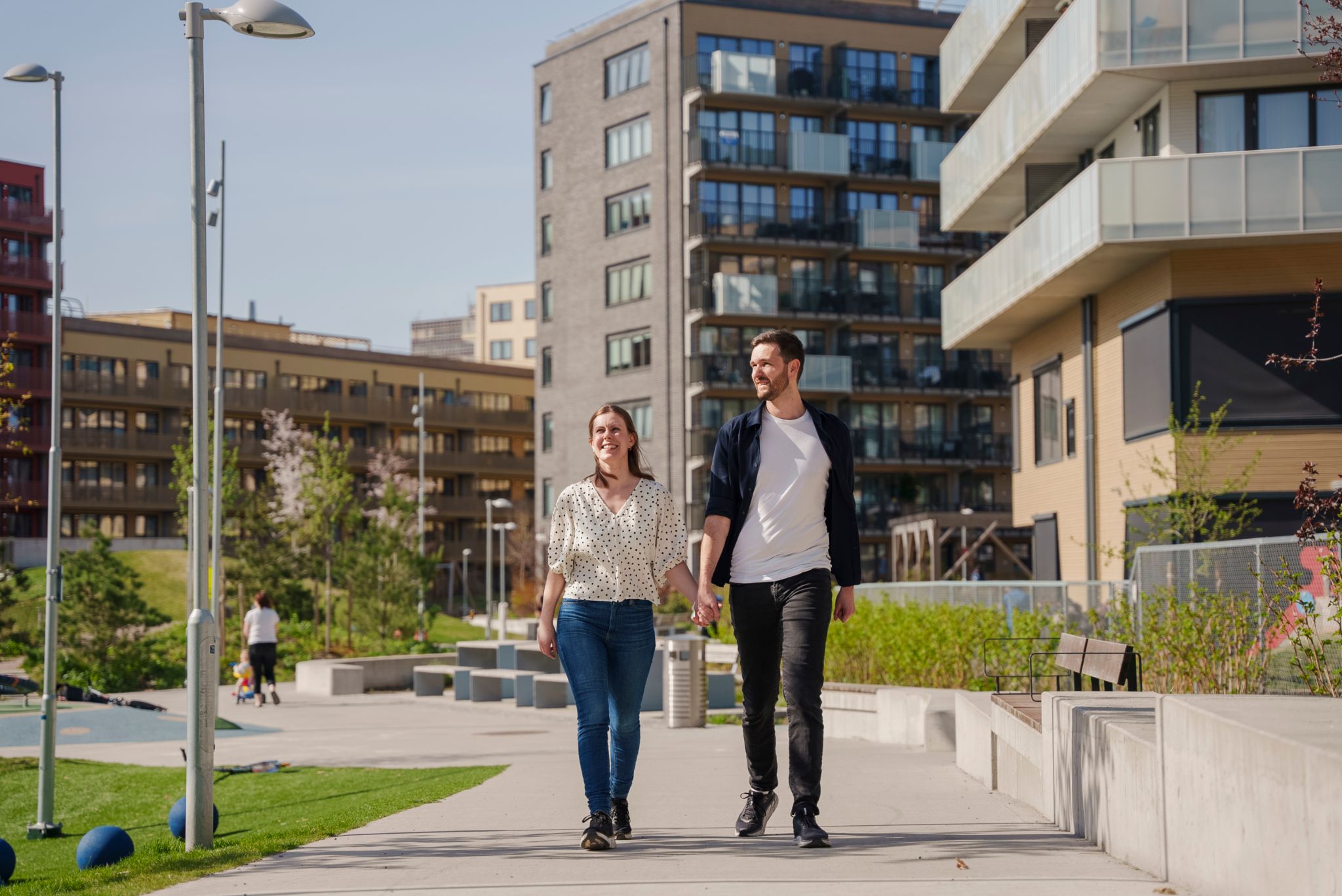 Bilde av et par som holder hender mens de går tur i et nabolag med leilighetsblokker.