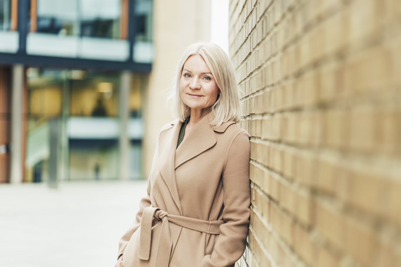 Trude Olaussen, leder for økonomisk kriminalitet i OBOS-banken, lener seg mot en murvegg