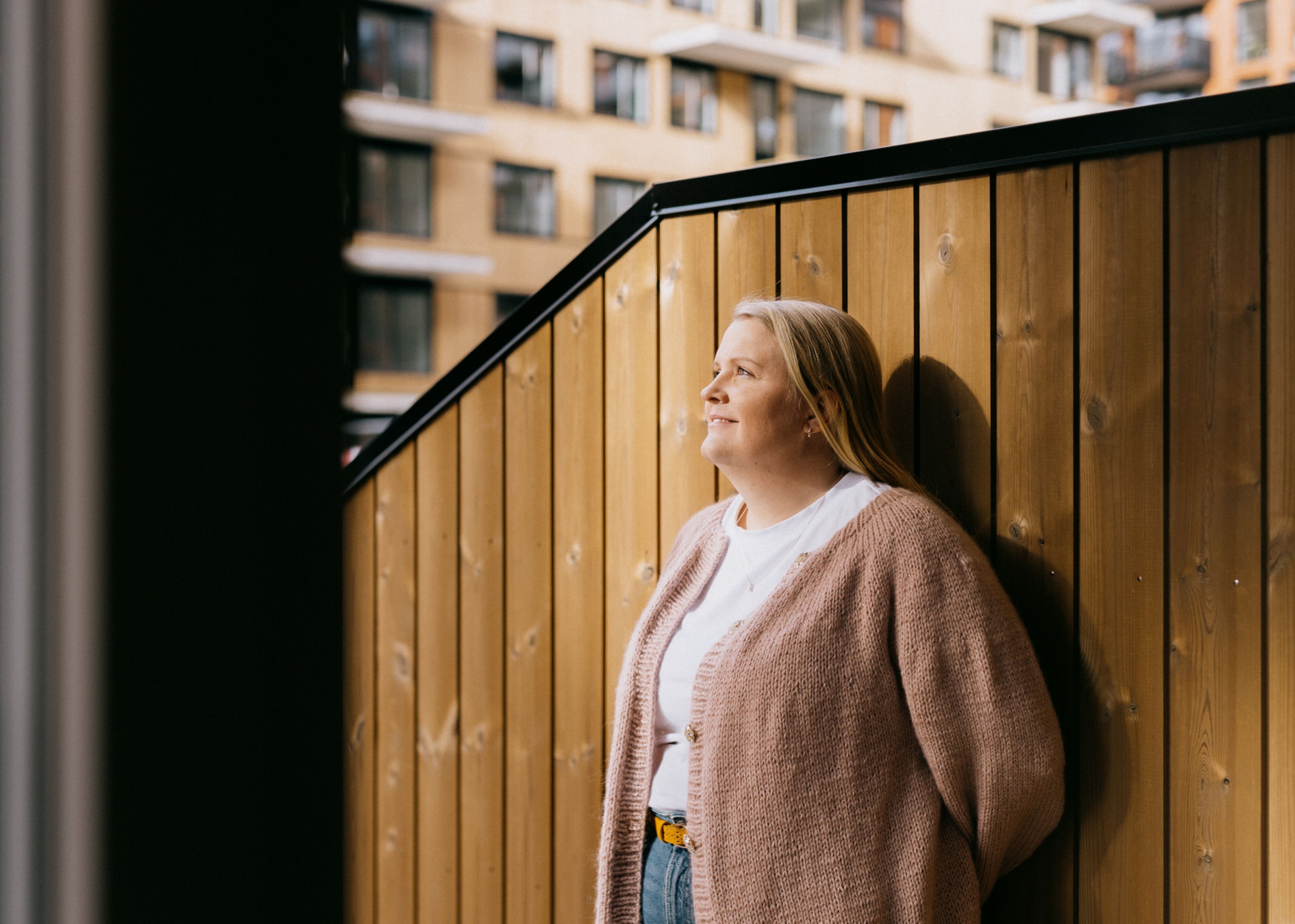 Josefin står inntil en trevegg og ser utover
