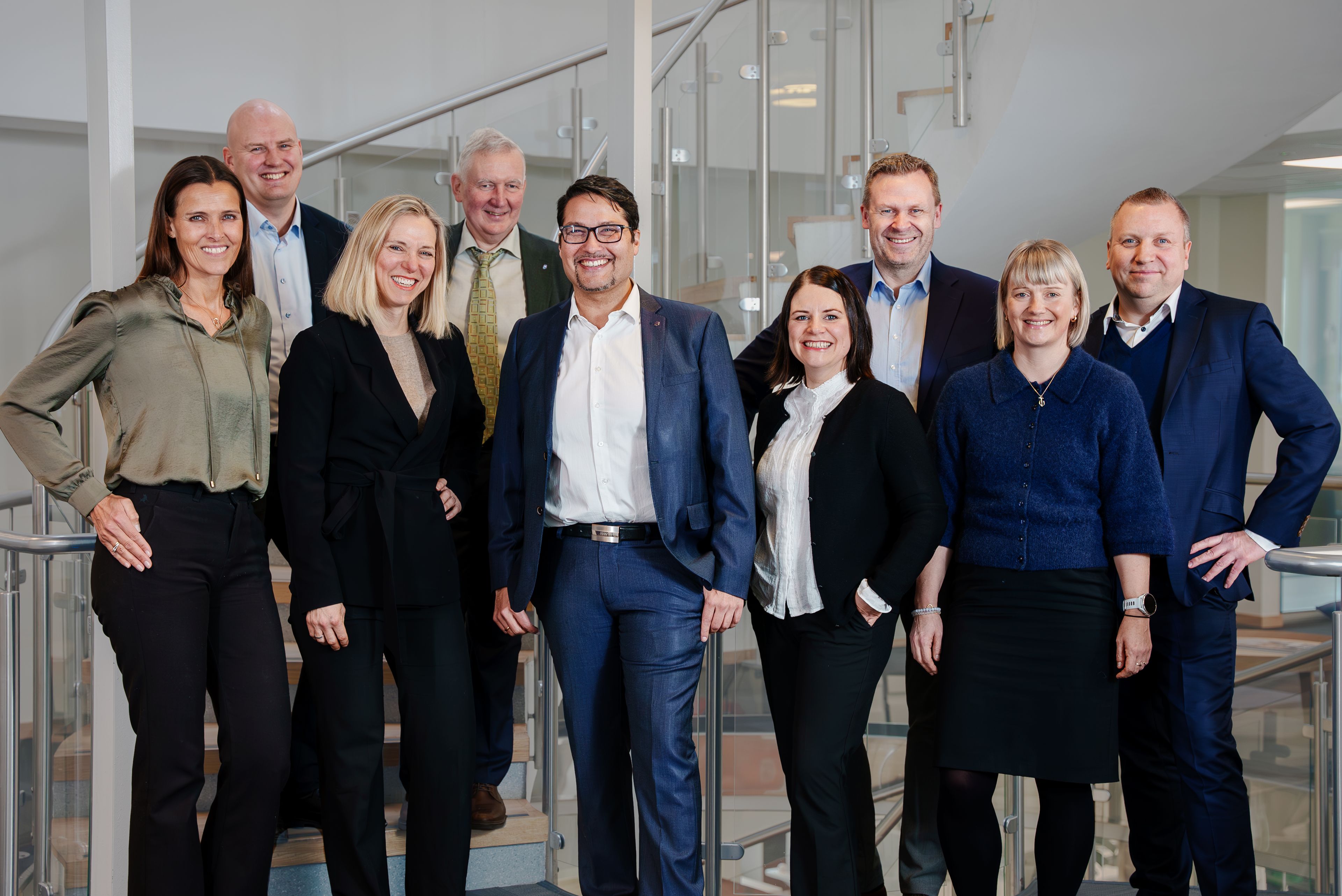 Konsernledelsen i OBOS poserer smilende foran en trapp.