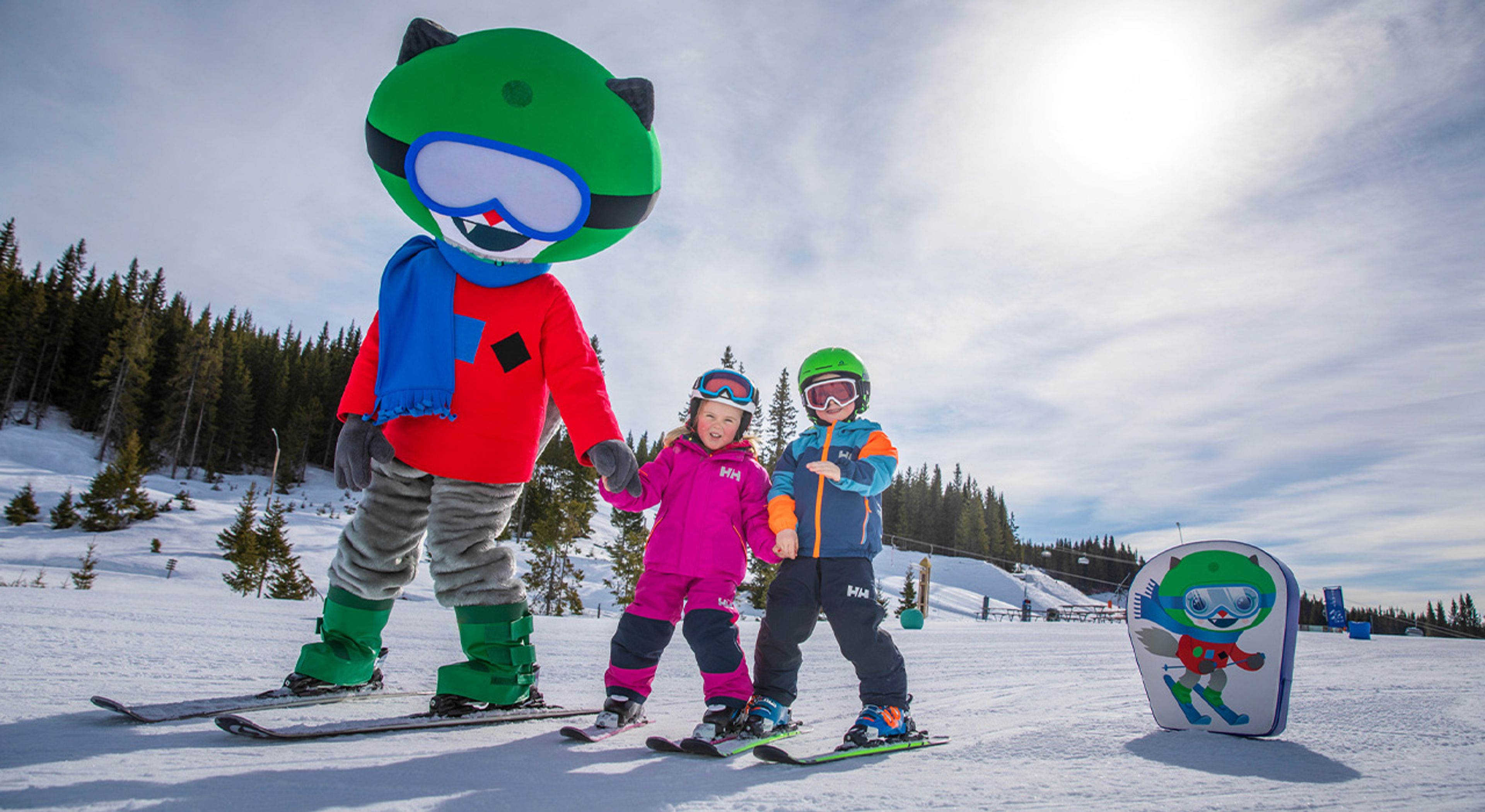 To barn på ski i slalåmbakken på Hafjell, sammen med maskotten Isa