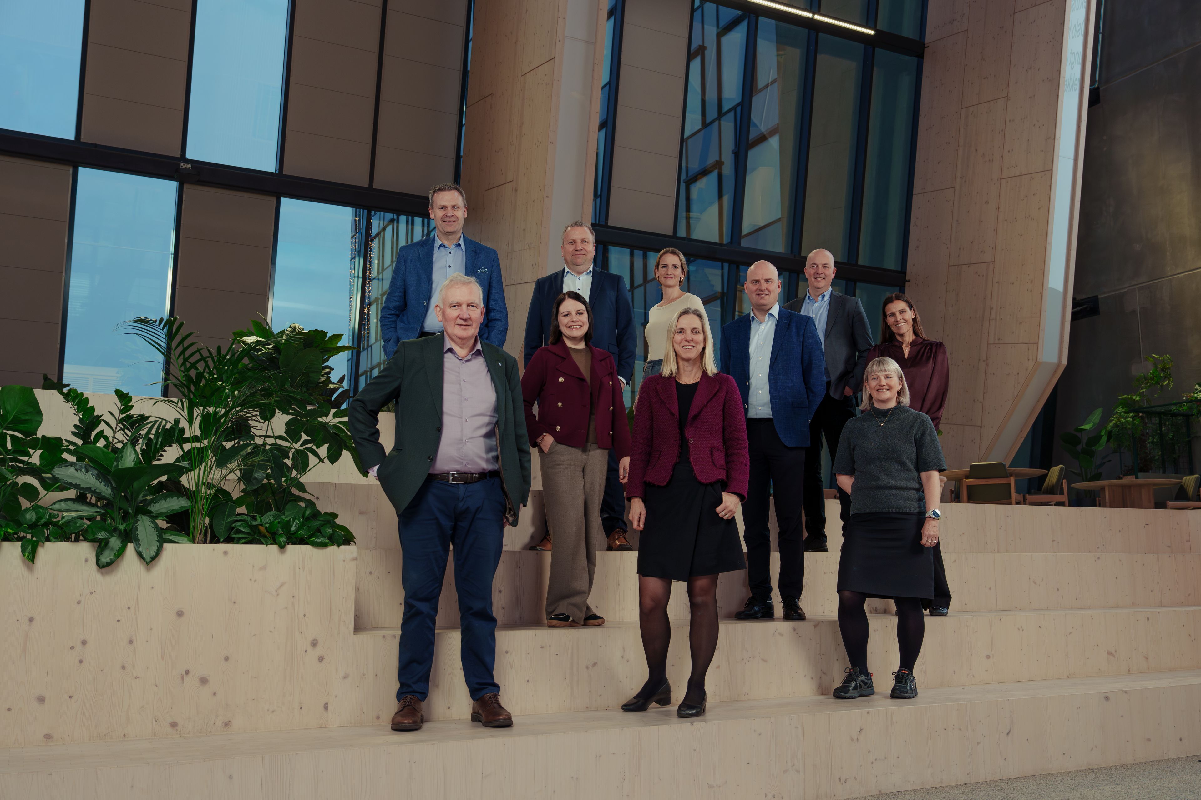 Konsernledelsen i OBOS poserer smilende foran en trapp.