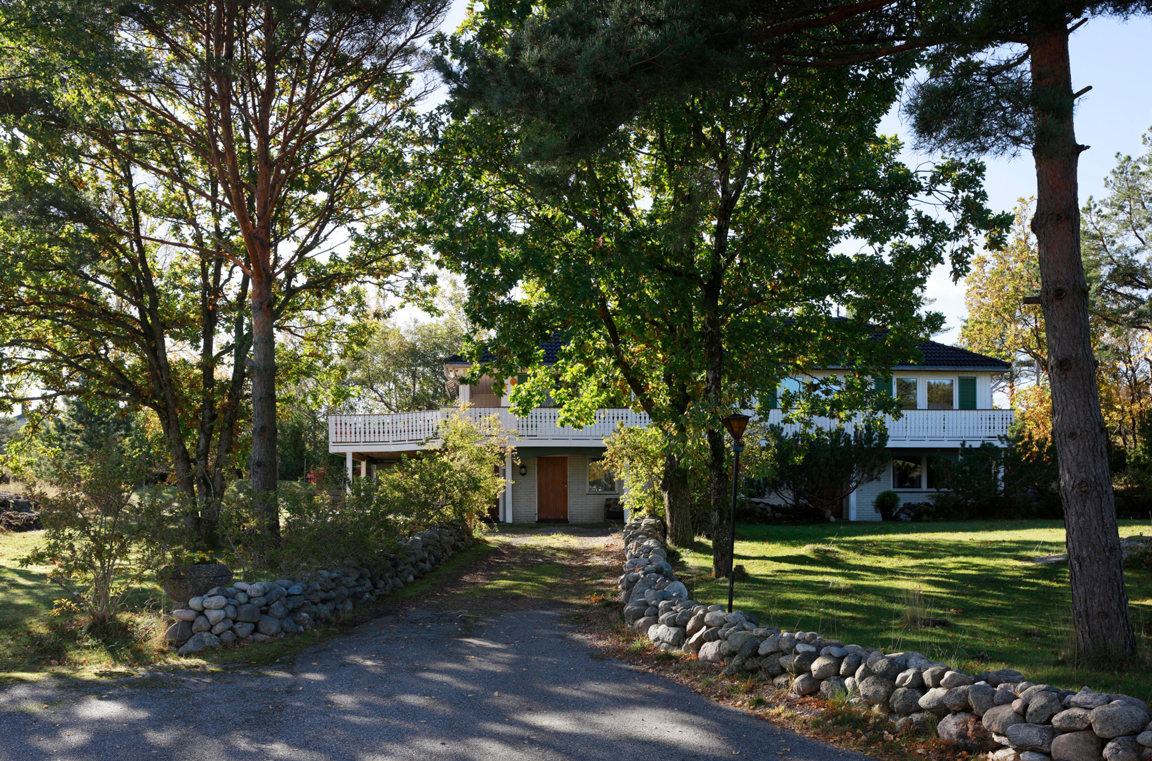 Bildet viser innkjørselen til et hvitt block watne-hus med trær rundt.