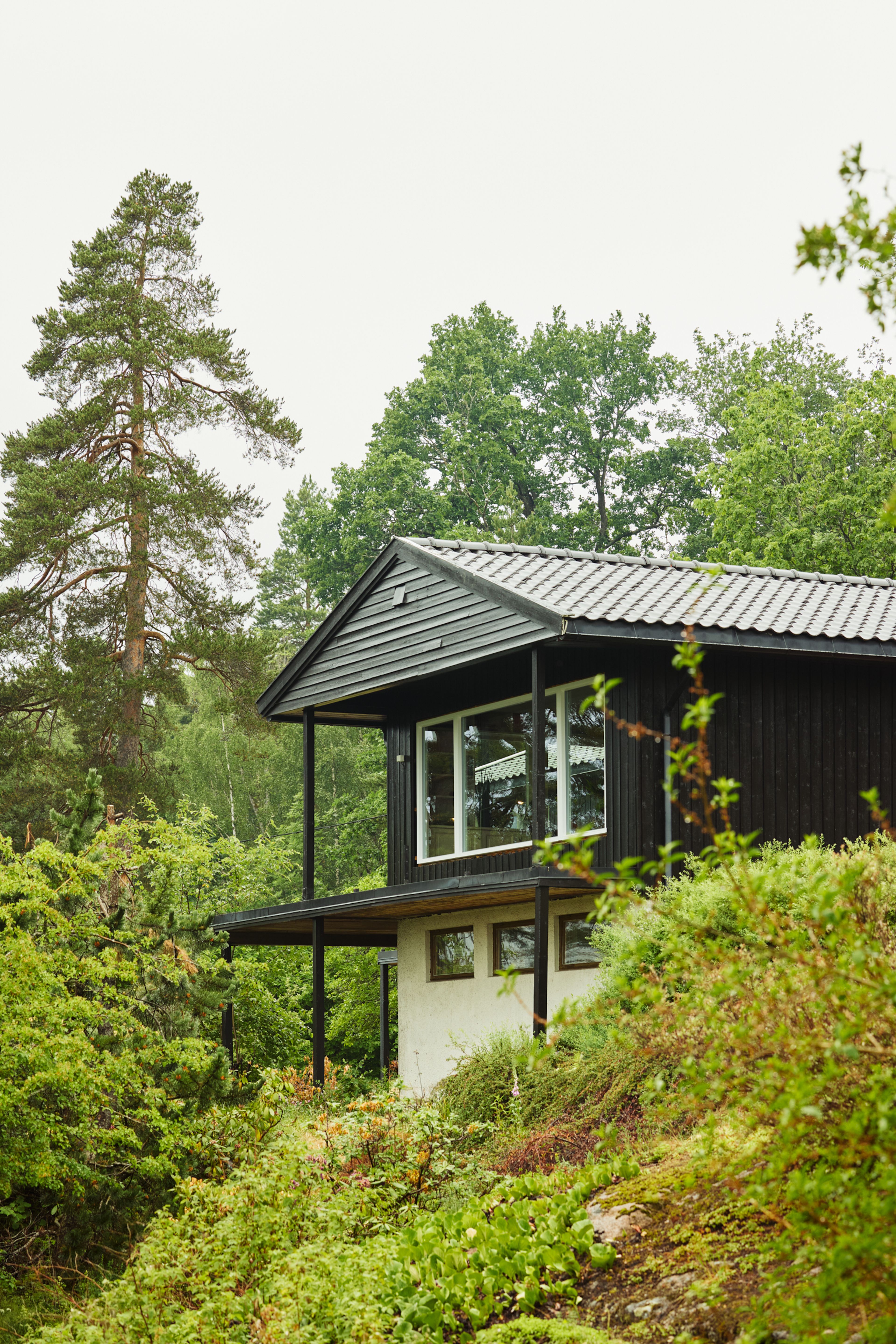 Bilde av huset fra utsiden. Huset er malt i en brunfarge som går godt sammen med de grønne omgivelsene.