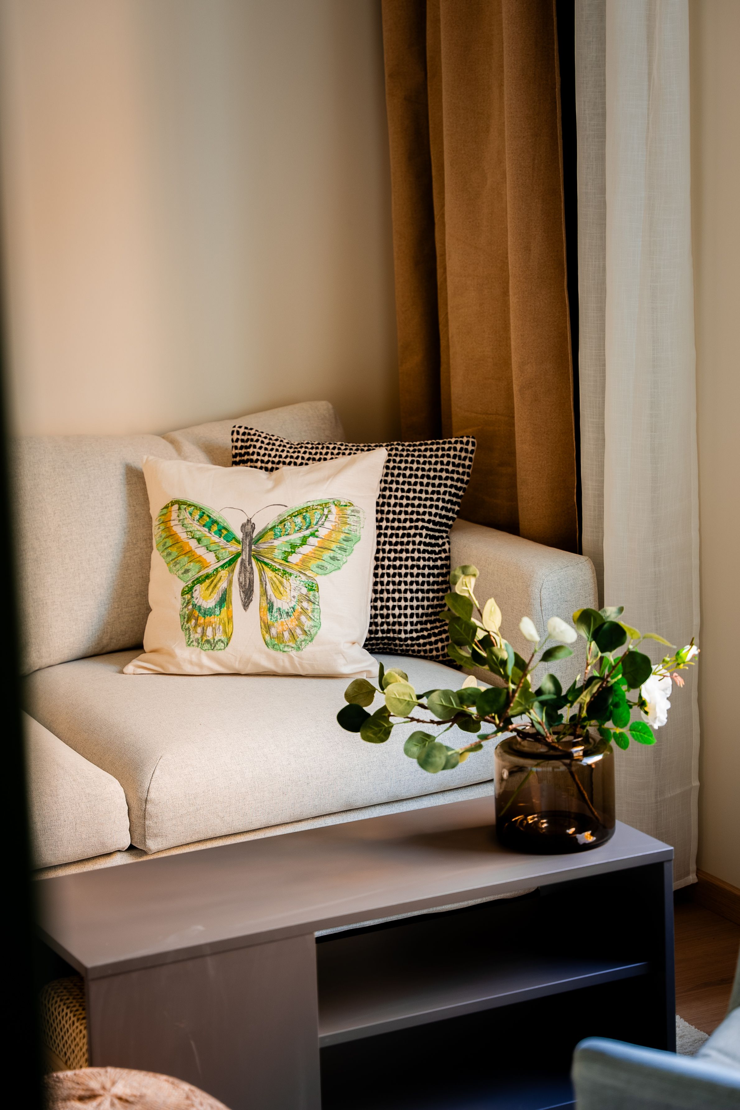 Puter i ulike fargetoner på en grå sofa med stuebord og en vase i forgrunnen.