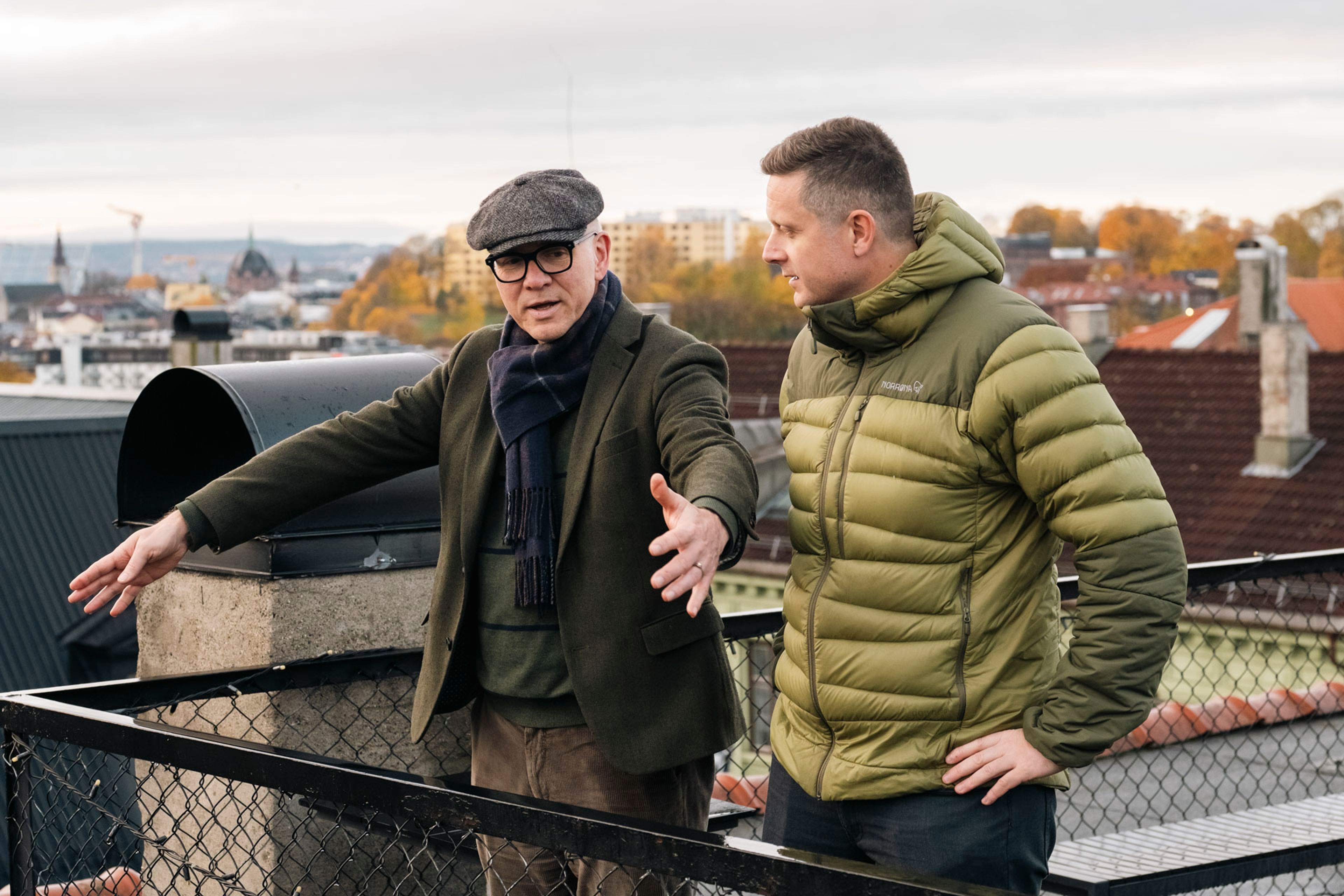 Styreleder Frank Martinsen og Morten Brustad Kjærland fra OBOS Prosjekt står på taket til Markveien 2 og diskuterer de planlagte energitiltakene, med utsikt over Oslo i bakgrunnen.