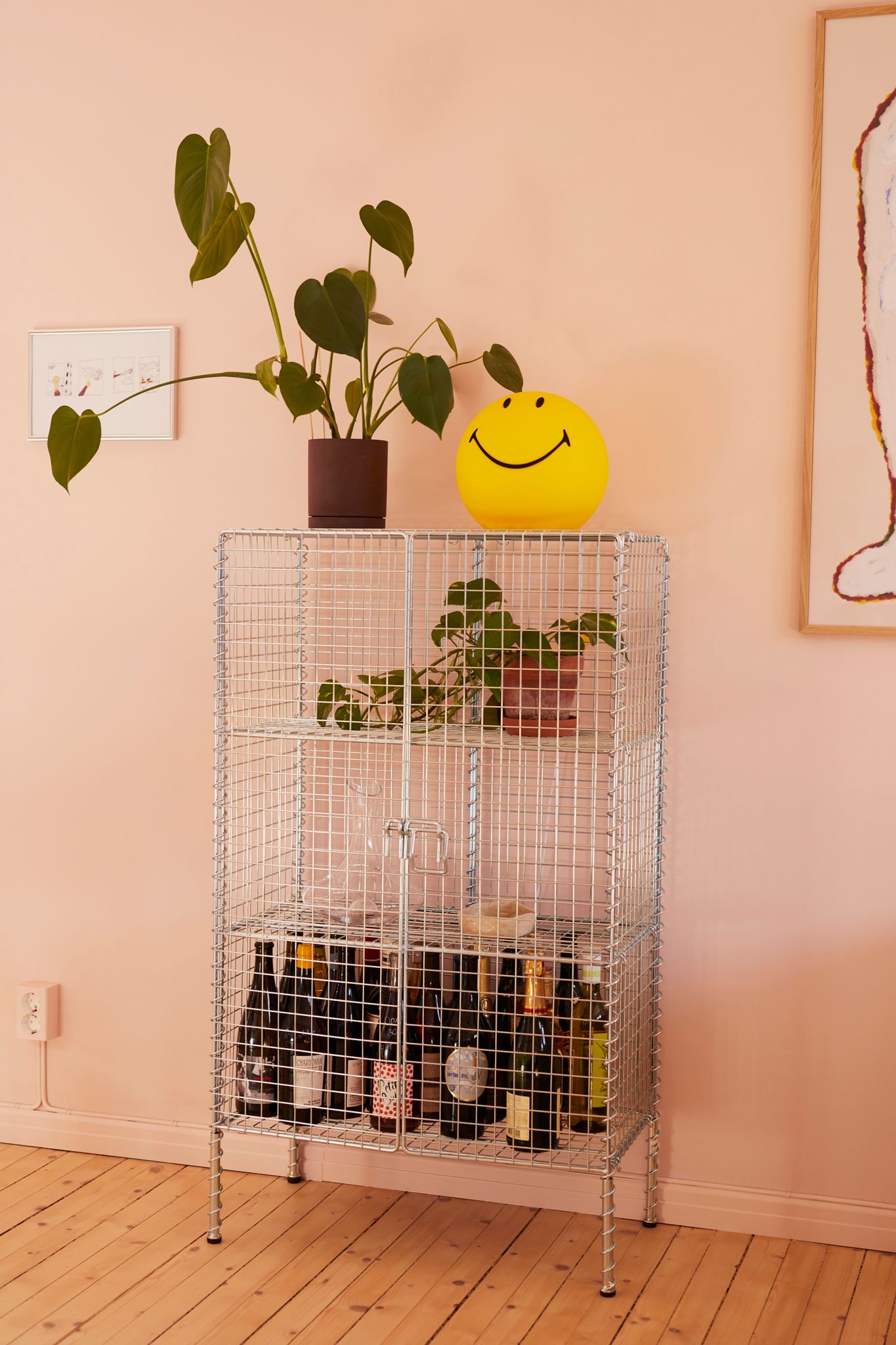 Skap i metall med en smiley-lampe og en plante oppå.