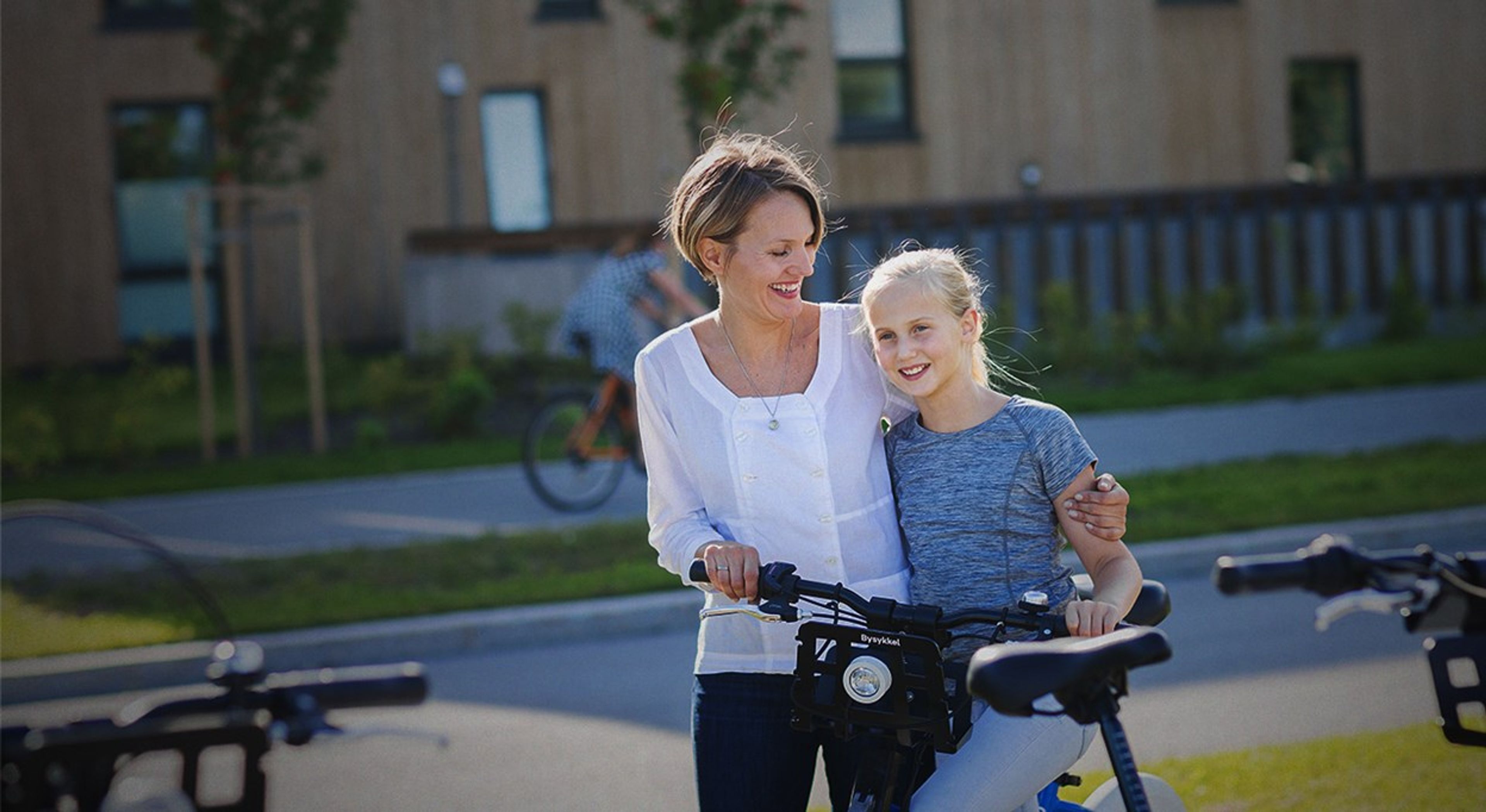 Bilde av mor av datter som smiler og sykler.