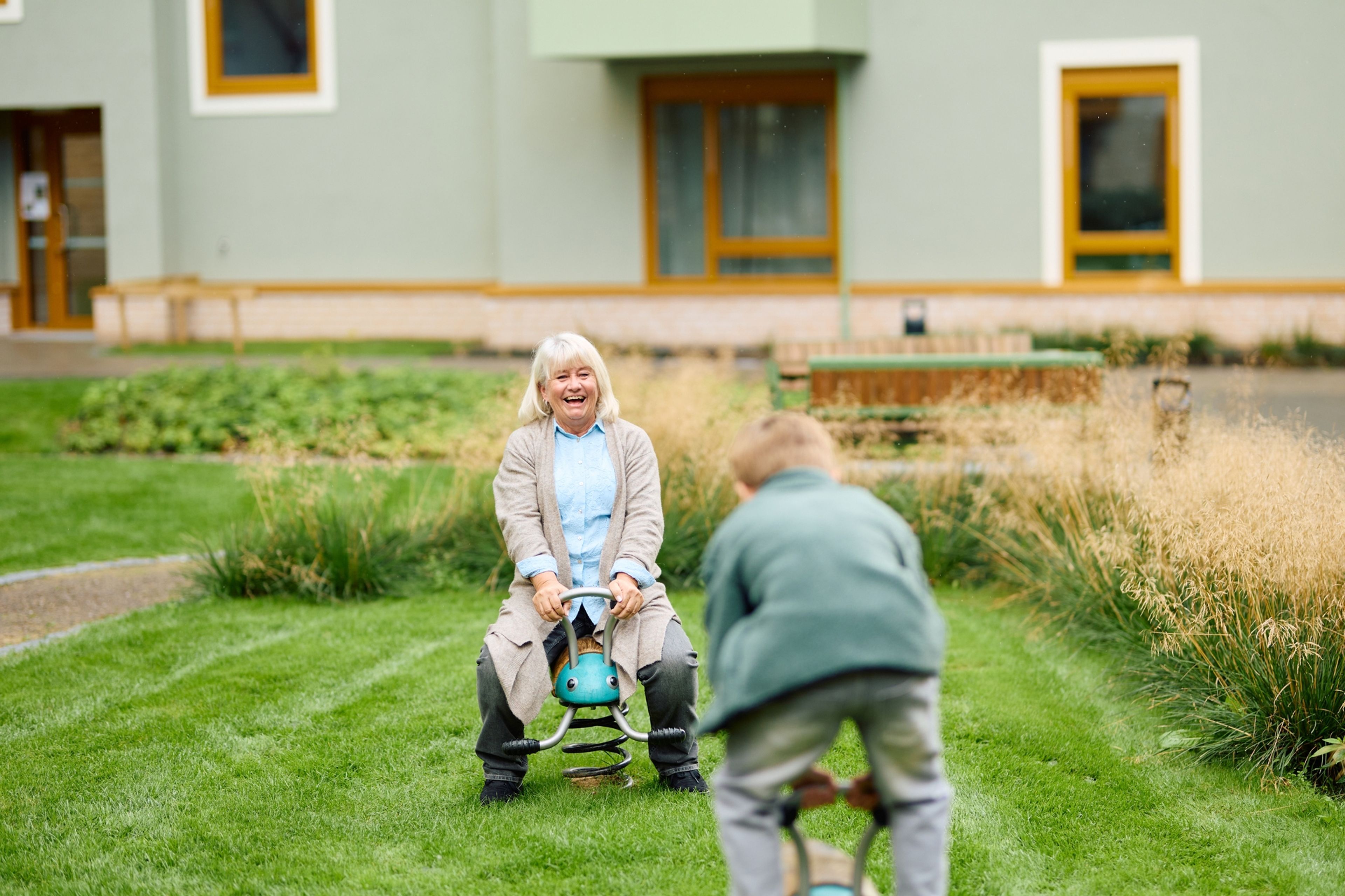 Bestemor og barnebarn leker i bakgården i et borettslag