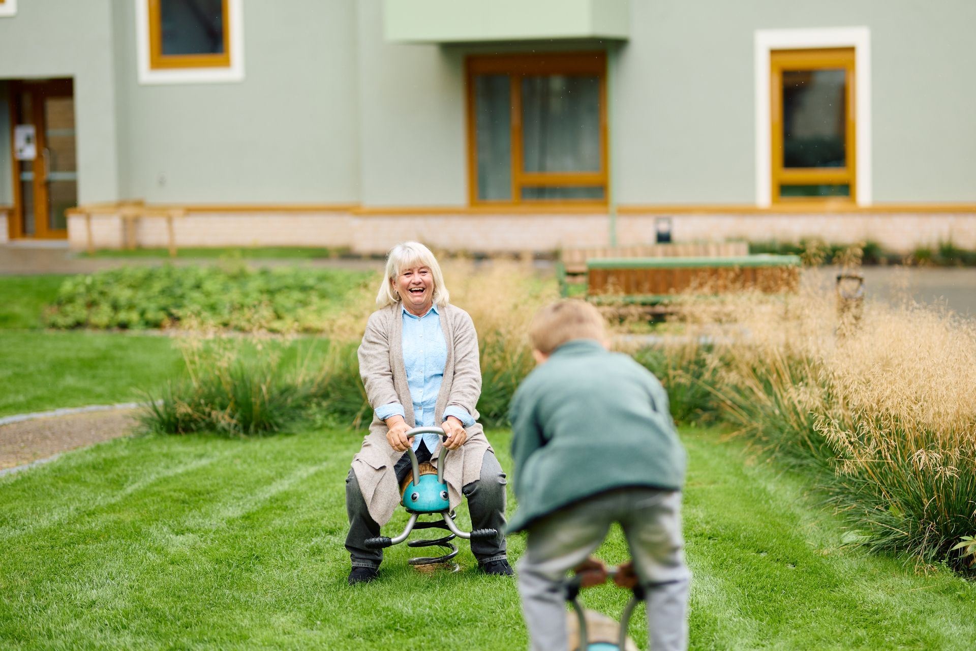 Bestemor og barnebarn leker i bakgården i et borettslag