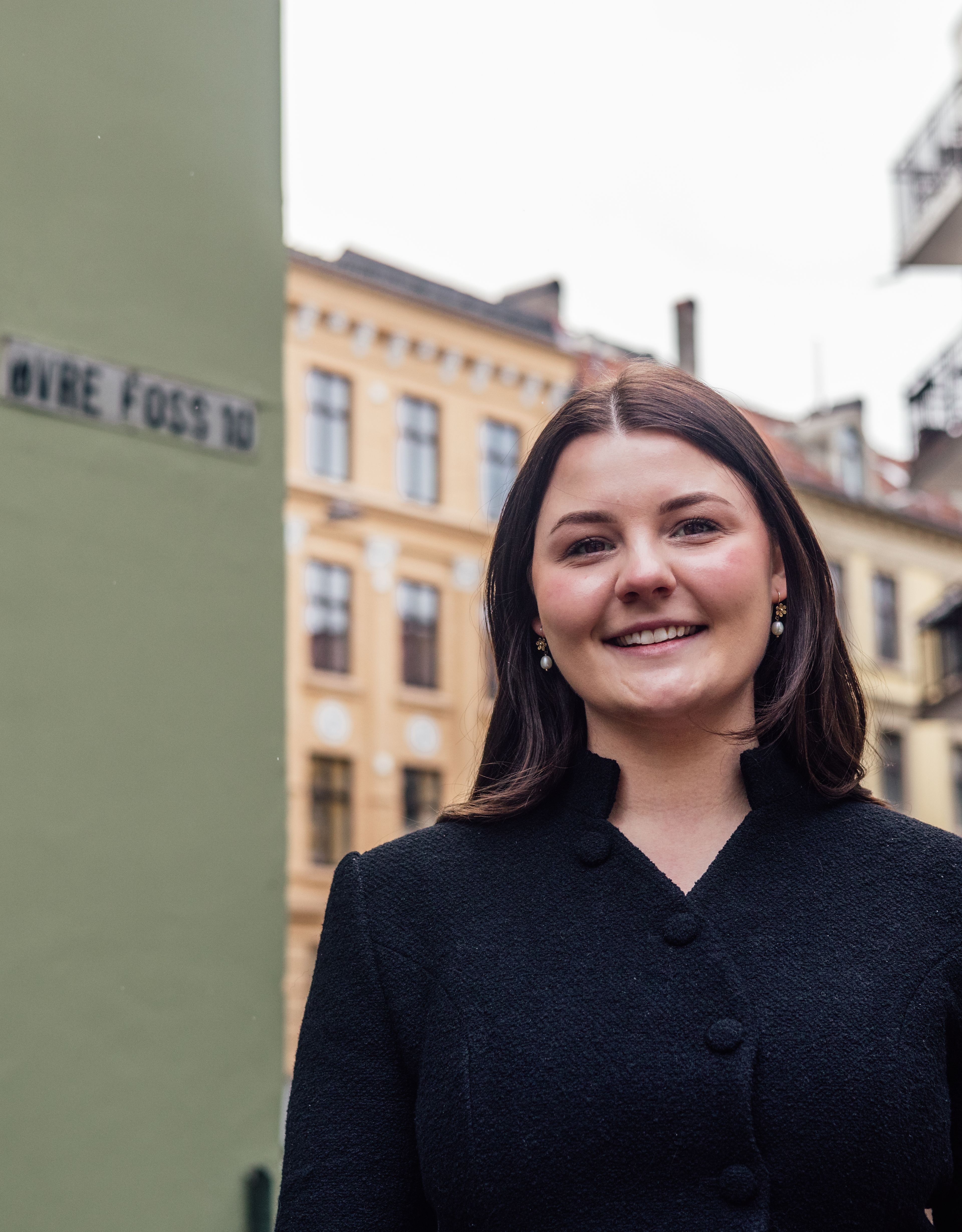 En smilende Nora Kristine foran inngangsdøra.