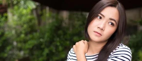 Woman in a striped top holding her shoulder outdoors