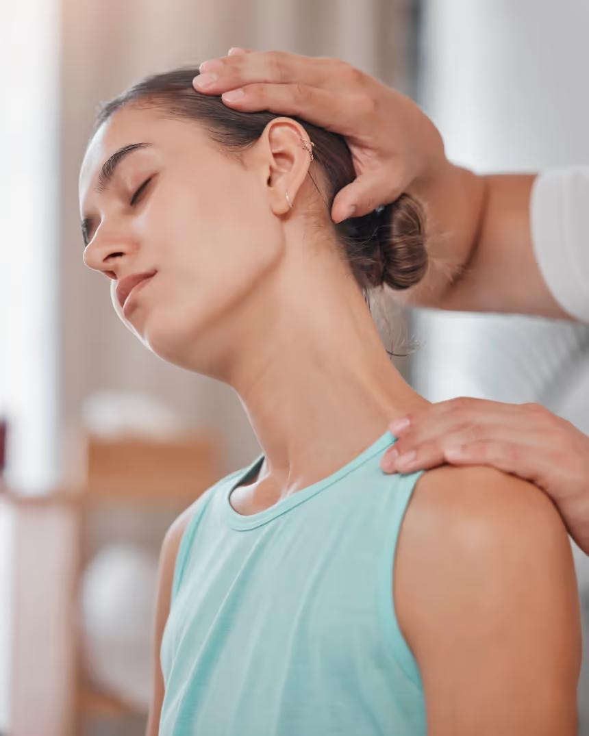 A practitioner tilting a woman’s head to one side, with one hand on her head and the other on her shoulder