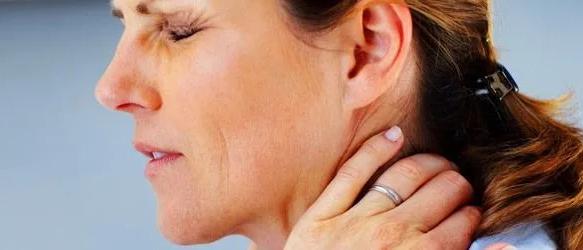 Woman with eyes shut in pain, holding the back of her neck