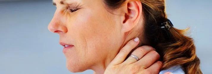 Woman with eyes shut in pain, holding the back of her neck