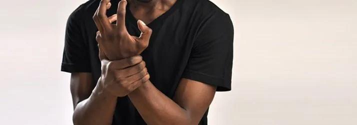 Man in a black T-shirt gripping his wrist