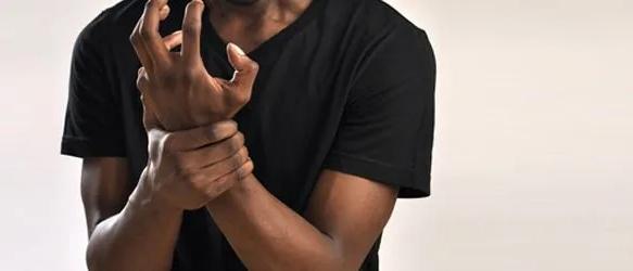Man in a black T-shirt gripping his wrist