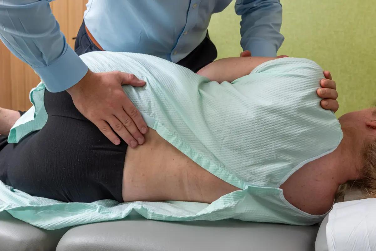 A chiropractor performing a hands-on lower back adjustment