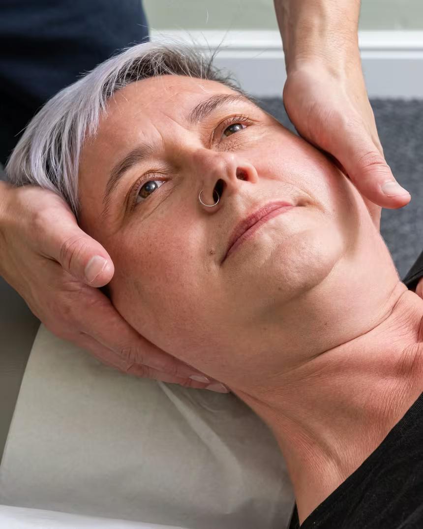 A gentle hold at the base of the skull during treatment