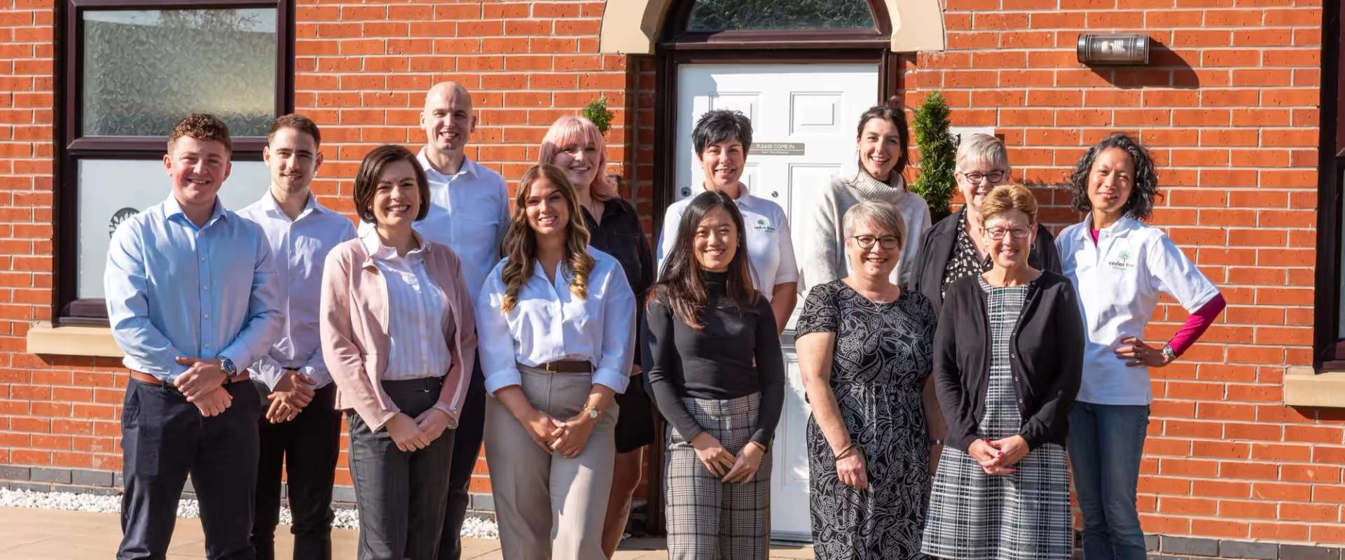 Members of the Cedar Tree Chiropractic team standing together outside a red-brick building
