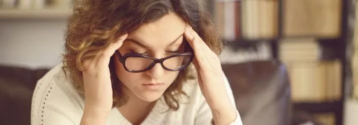 Woman in glasses pressing her fingers to her temples