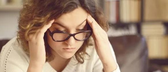 Woman in glasses pressing her fingers to her temples