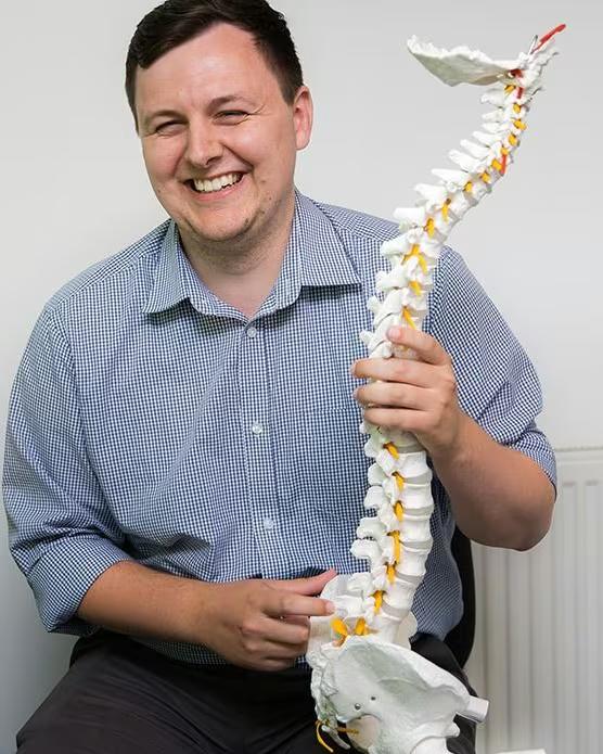 A chiropractor holding a model of the spine