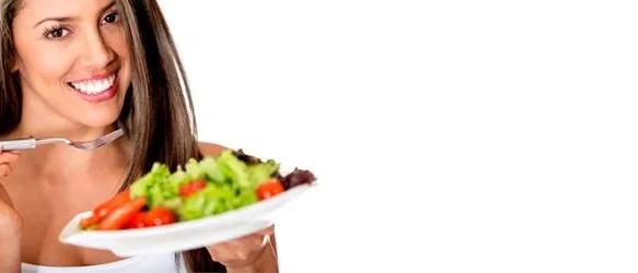Smiling woman holding a fork and a plate of salad