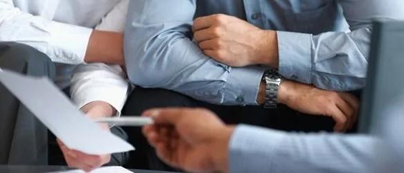 People seated at a desk with papers being passed across