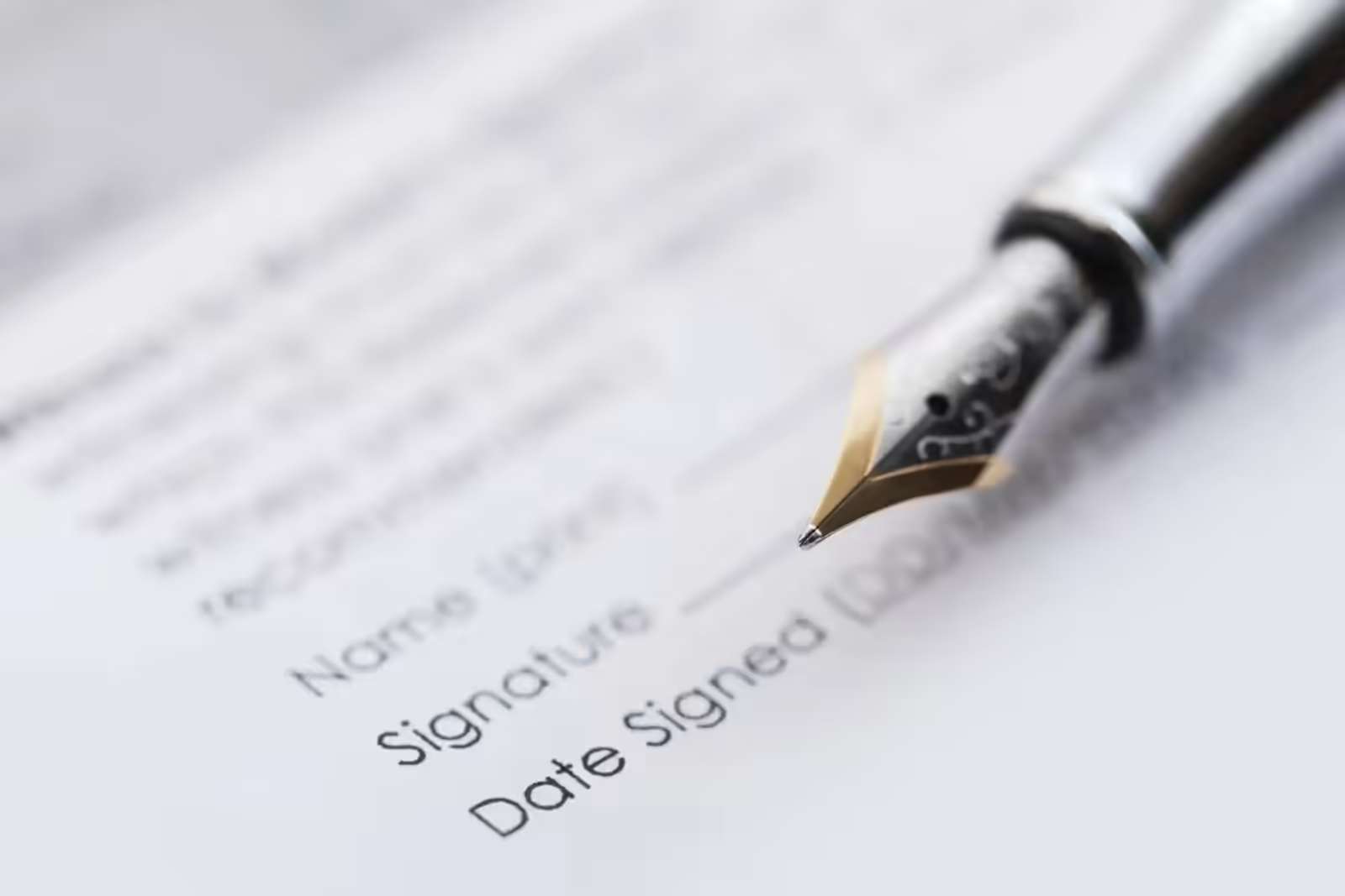 A fountain pen resting on a printed form beside the name, signature and date lines