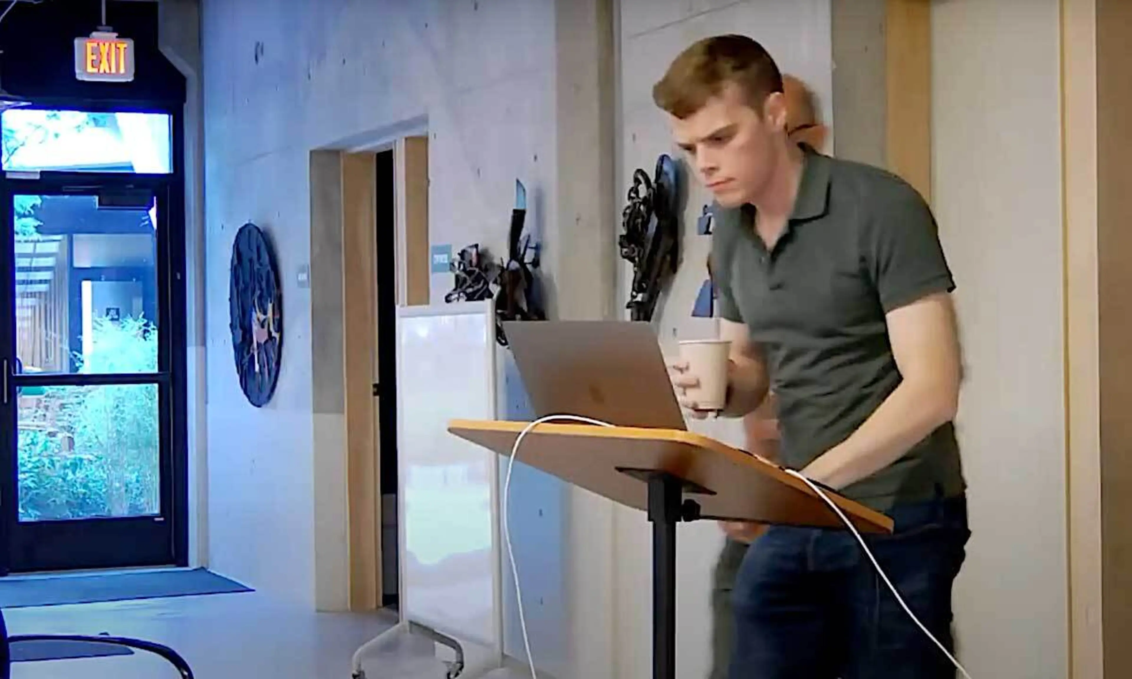 A man holding glass in hand and working on laptop while standing