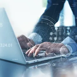 A man in a suit typing on a laptop