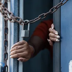 A hand reaches through a chained door