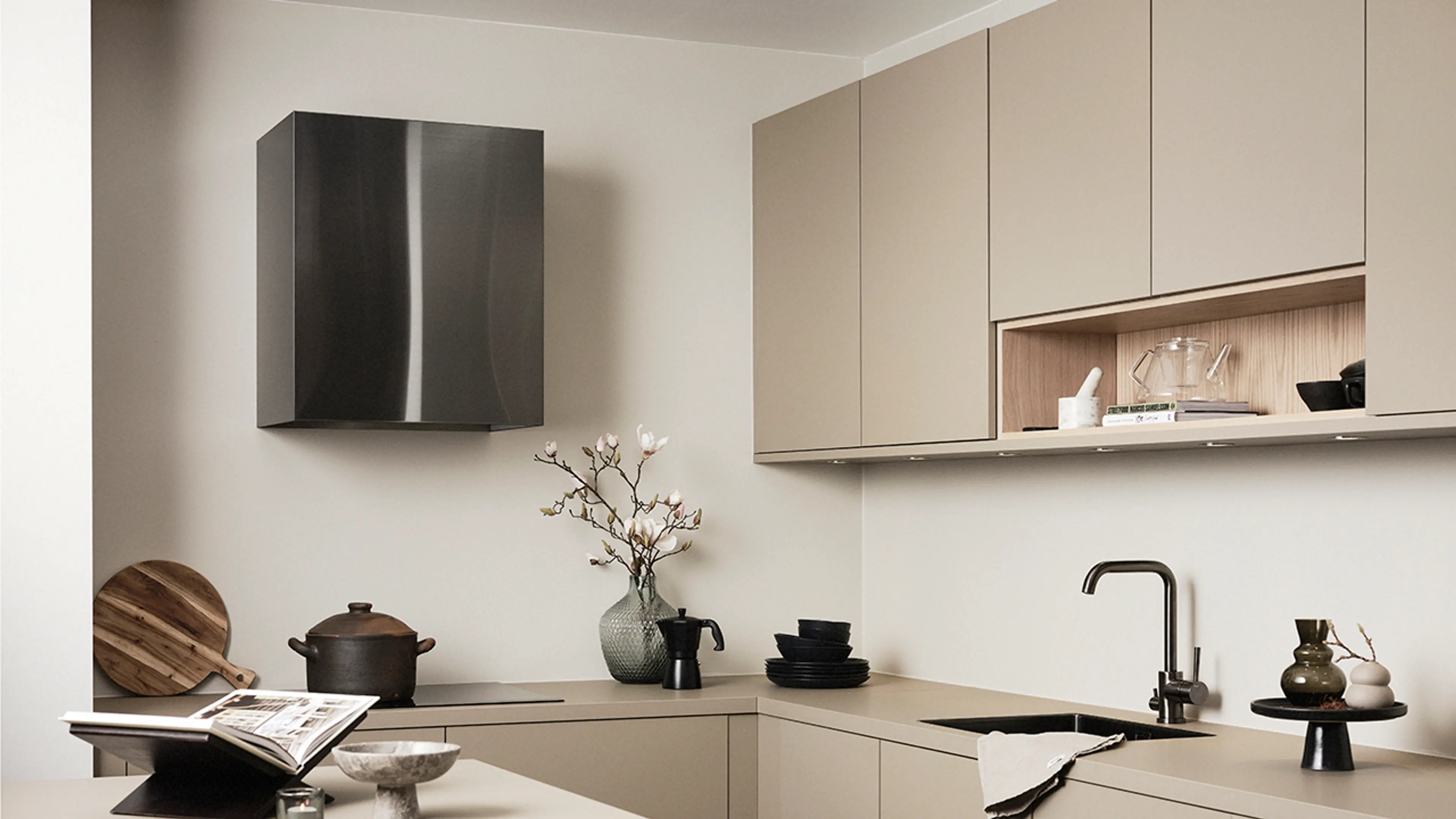 Veggmontert kjøkkenvifte i svart stål i lyst kjøkken.