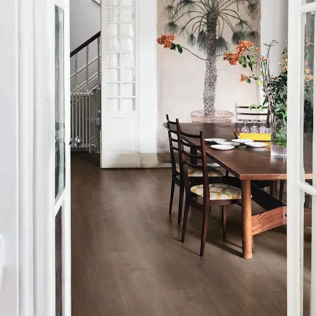 Mørkt gulv i spisestue med tremøbler og palmetapet