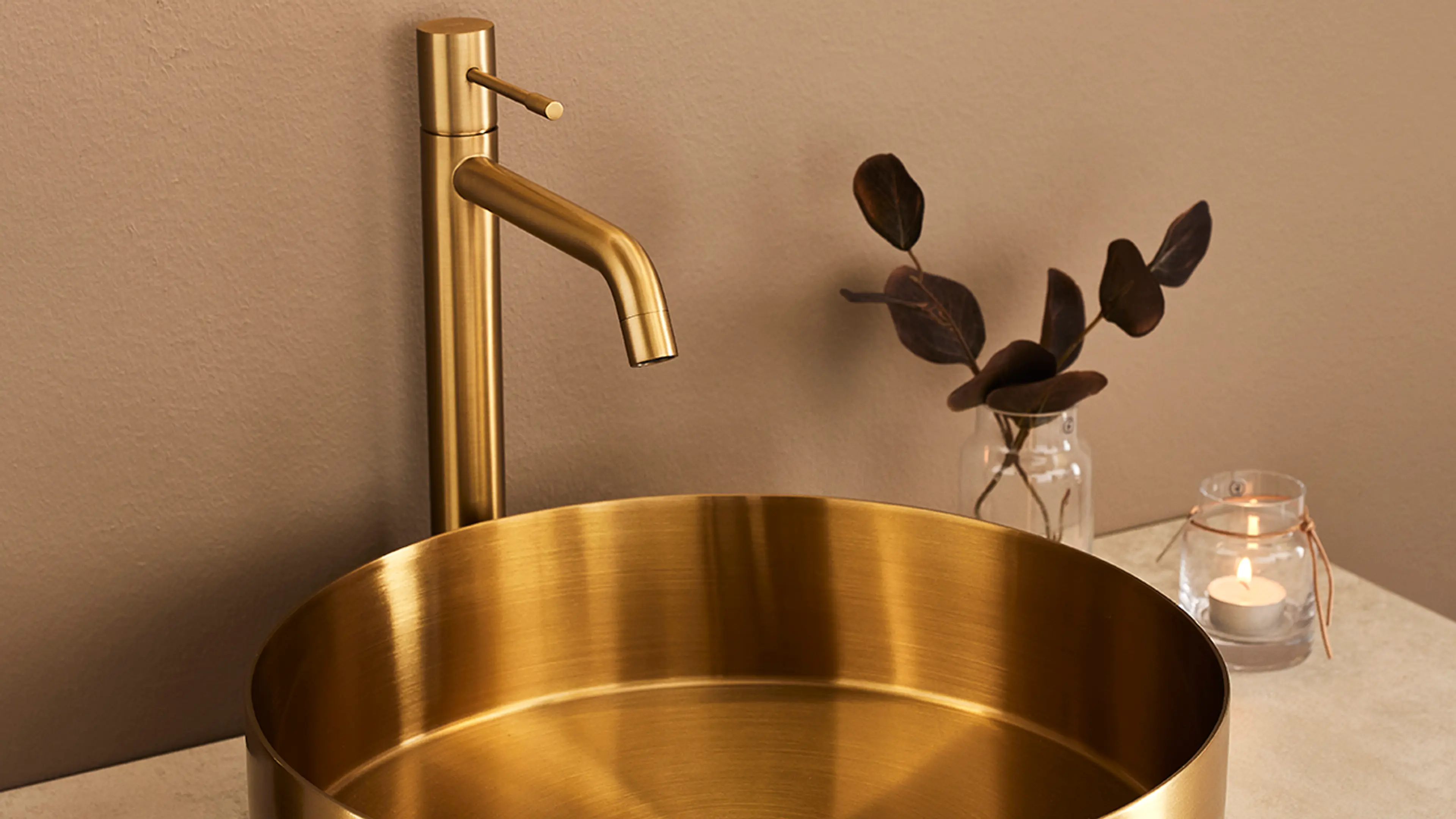 Messingservant og -armatur på beige baderom.