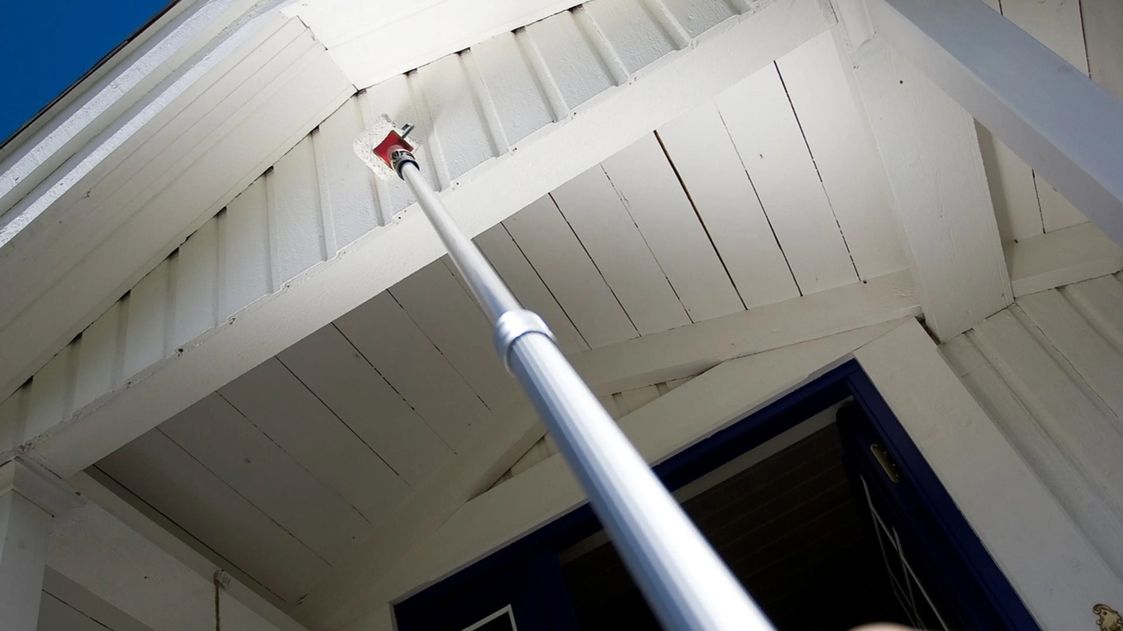 Hvitt hus som males med landskaft og rulle.