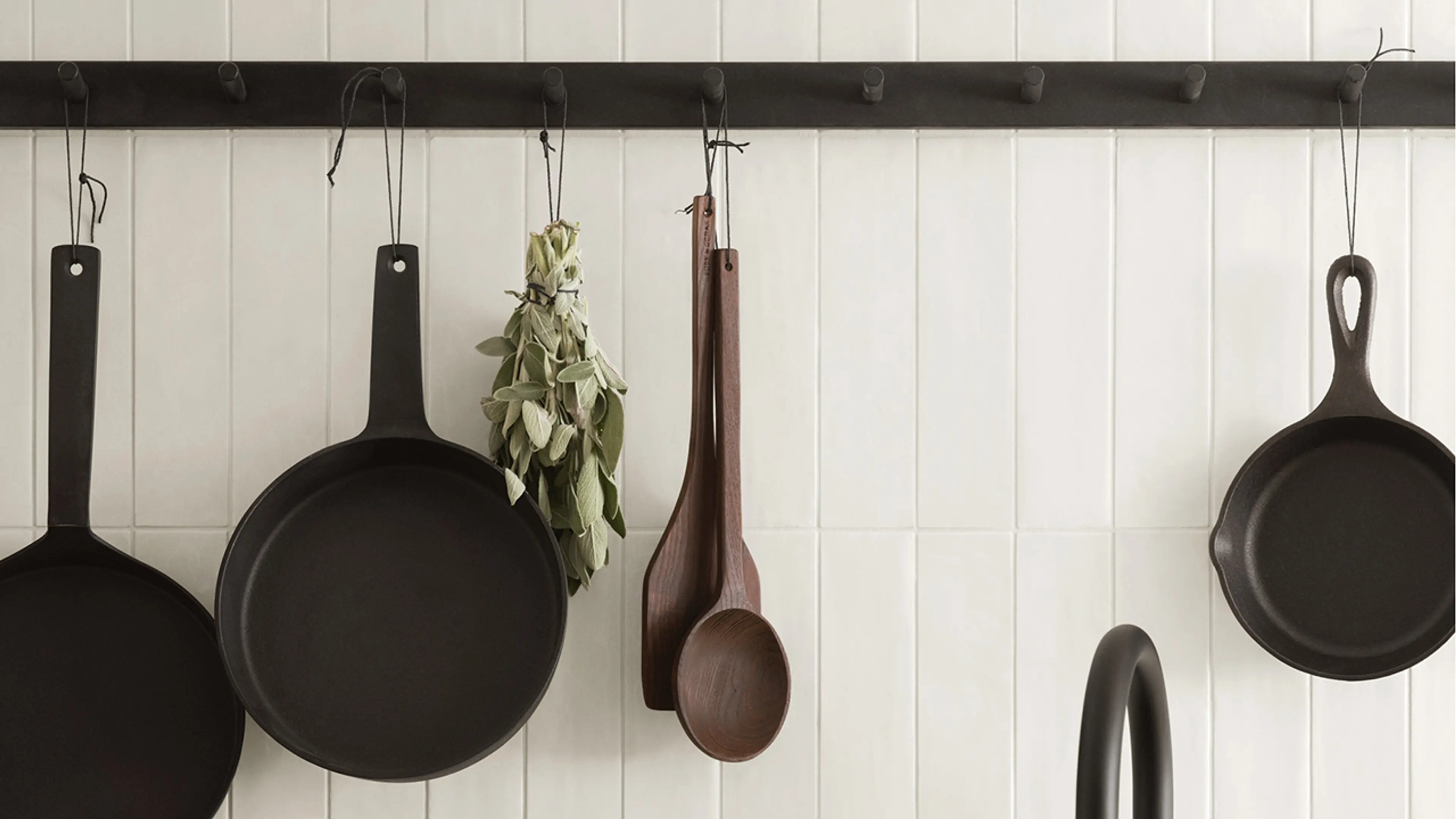 Hyttekjøkken med knaggrekke til oppbevaring av stekepanner og kjøkkenredskaper.